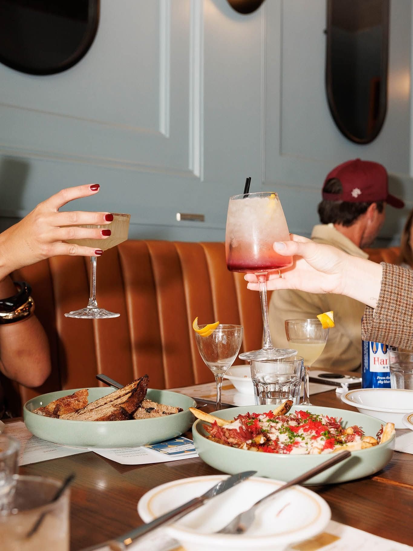 Table setting with drinks and plates at an upscale restaurant with leather booth seating.
