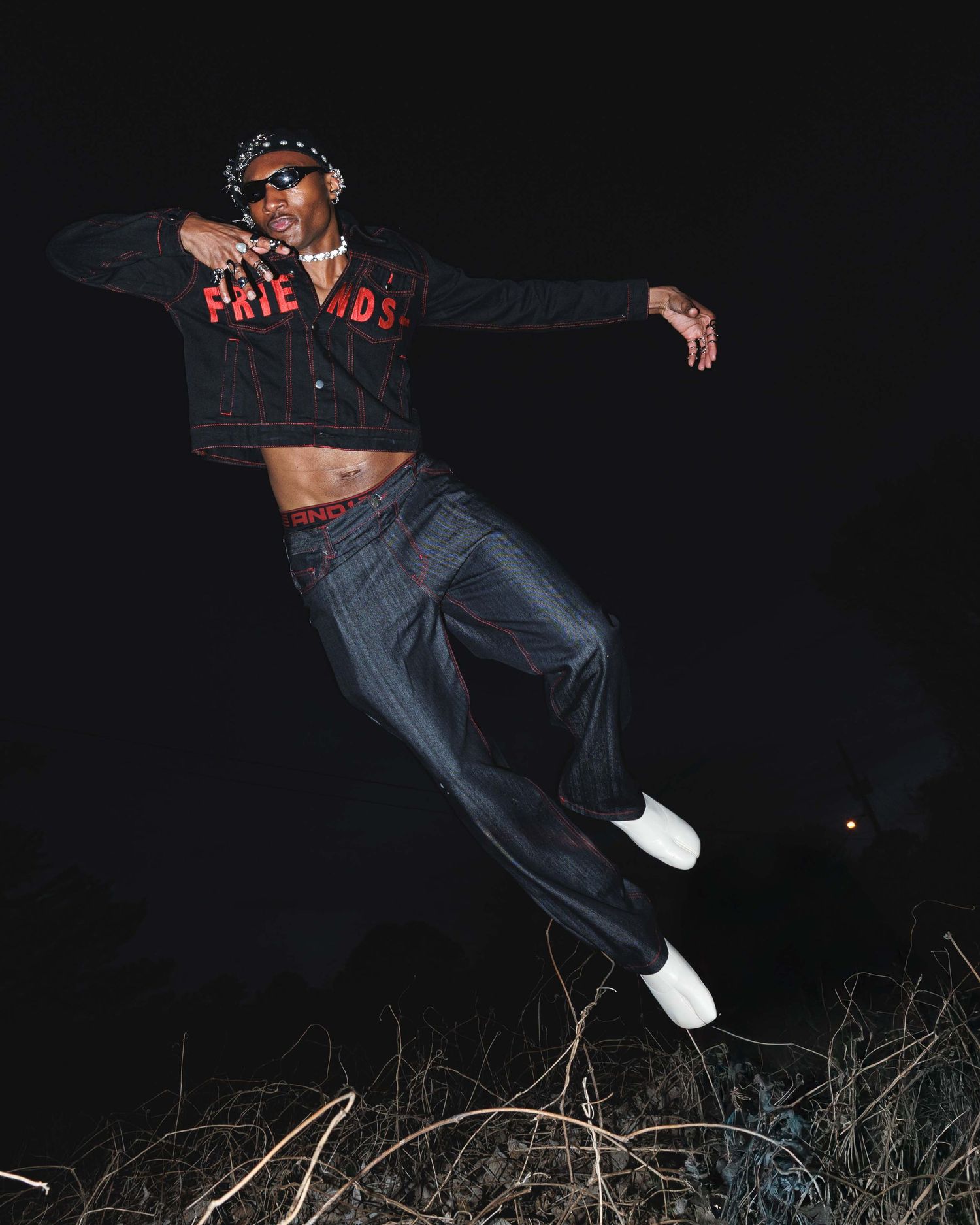 Editorial fashion photograph capturing a model suspended mid-air at night, emphasizing movement, energy, and cinematic storytelling.