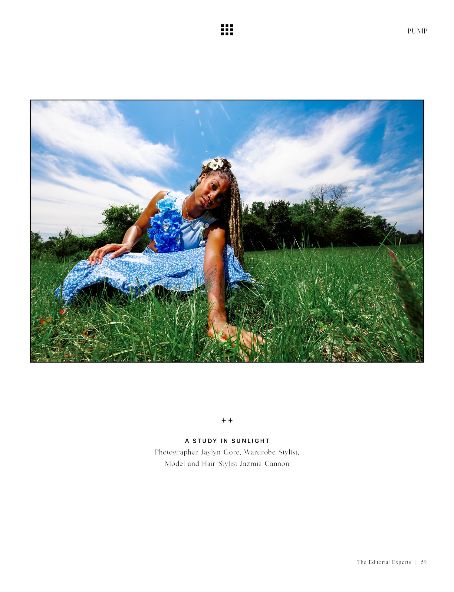 Woman in blue floral dress poses gracefully in green field under blue sky, editorial fashion shoot titled A Study in Sunlight.