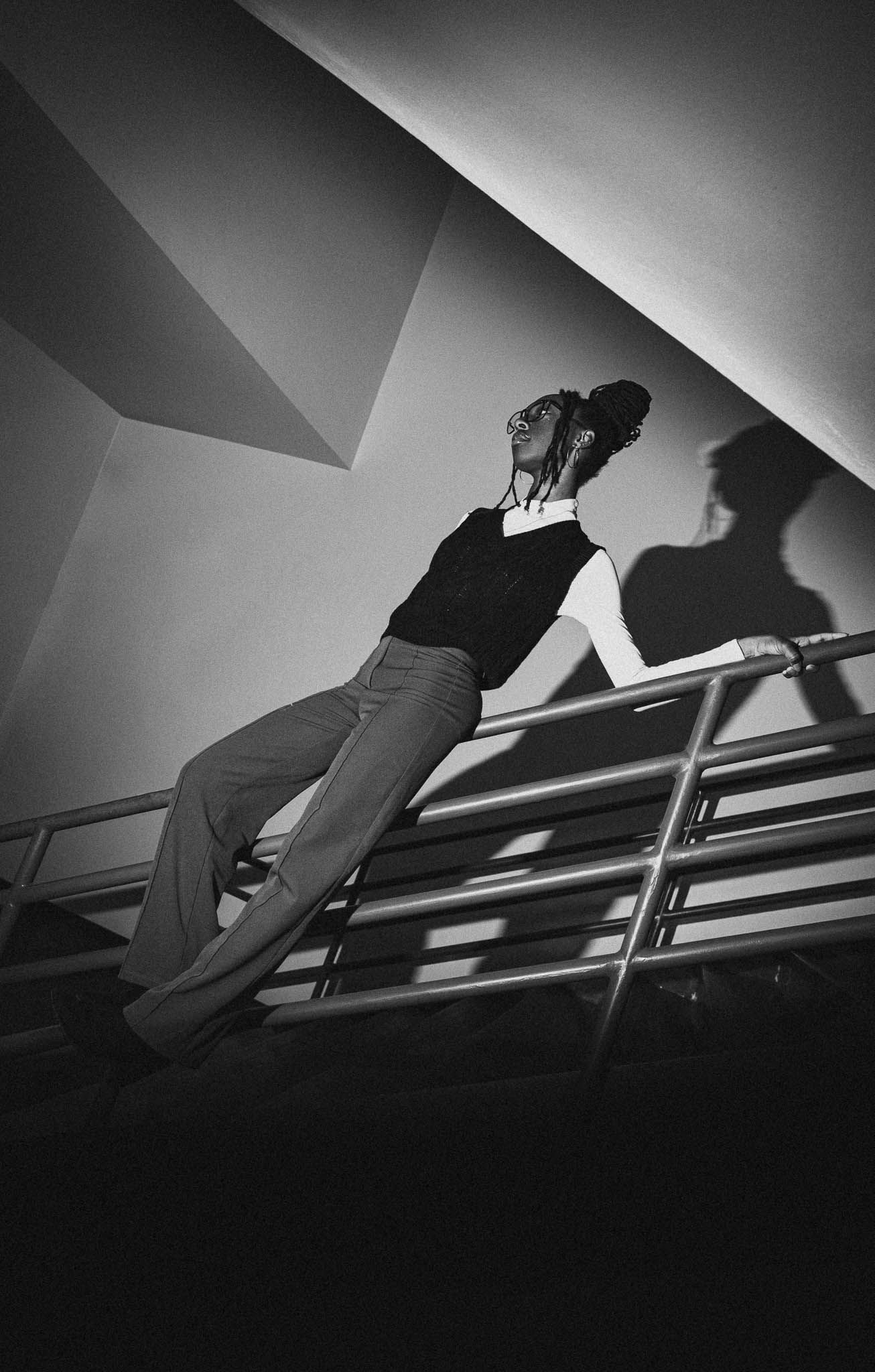 Dramatic low angle black and white shot of a person leaning back on metal railings.