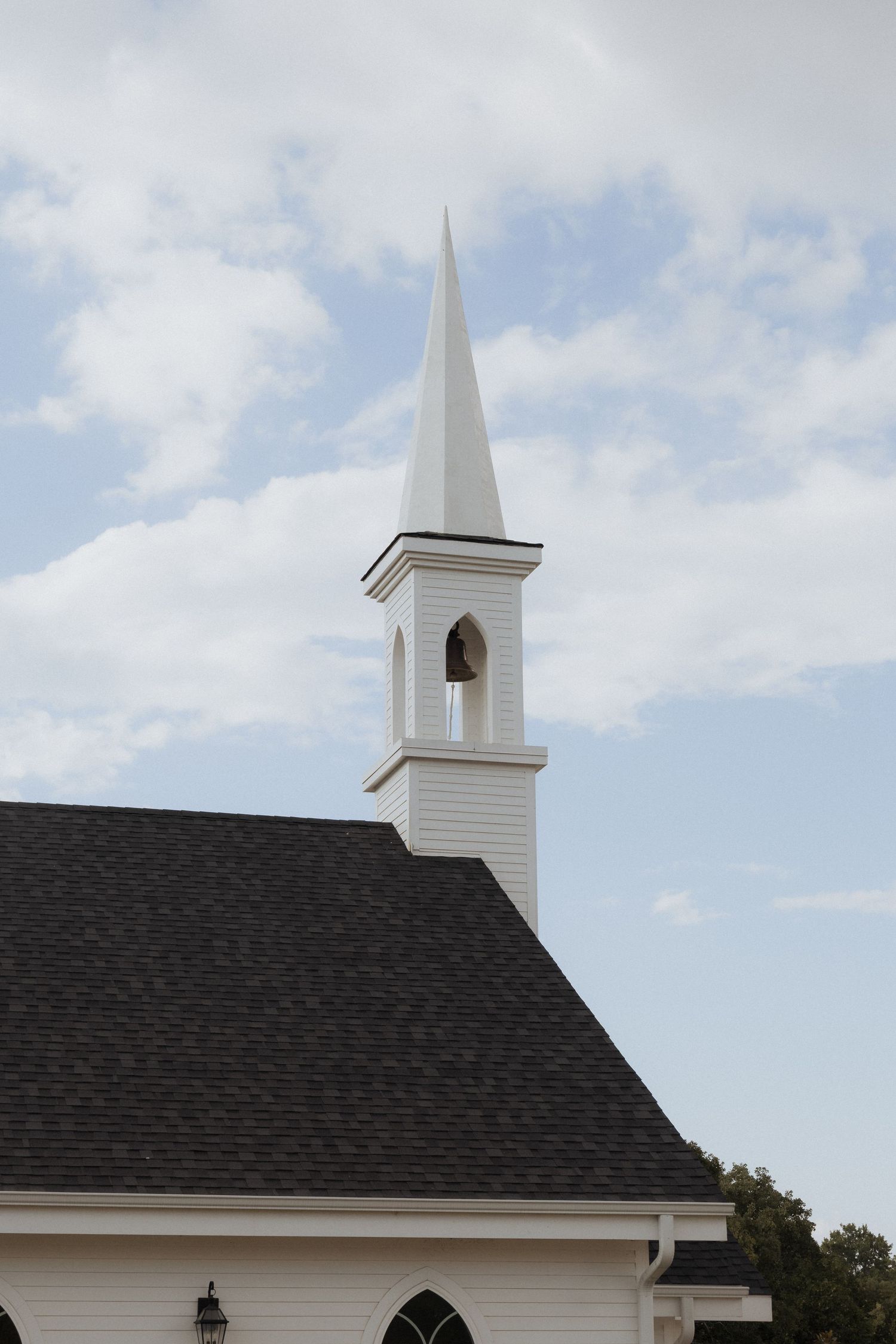 White church steeple with pointed spire rises against a cloudy blue sky, viewed from different angles.