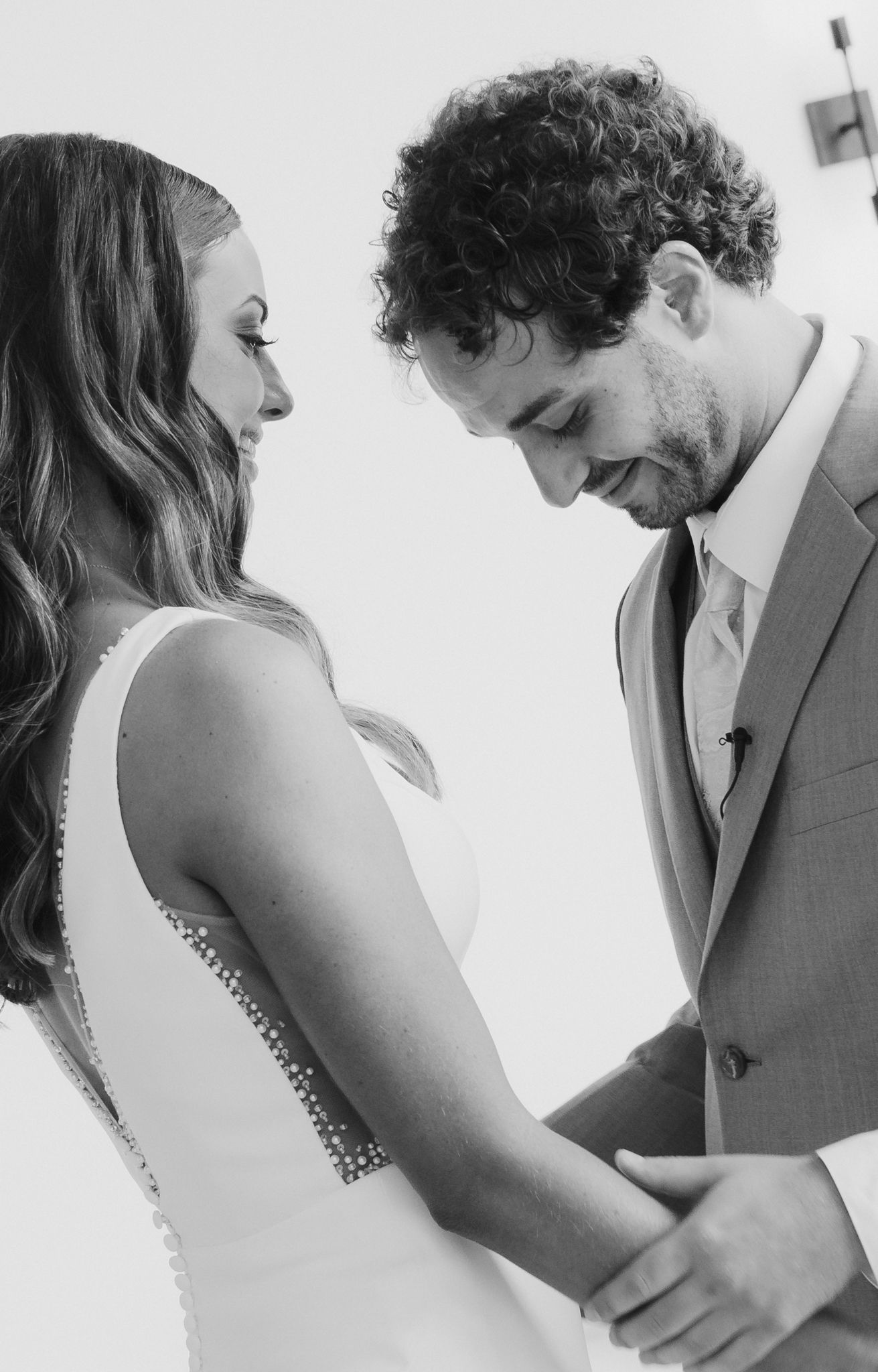 A black and white wedding photo capturing an intimate moment between newlyweds dressed in formal attire.