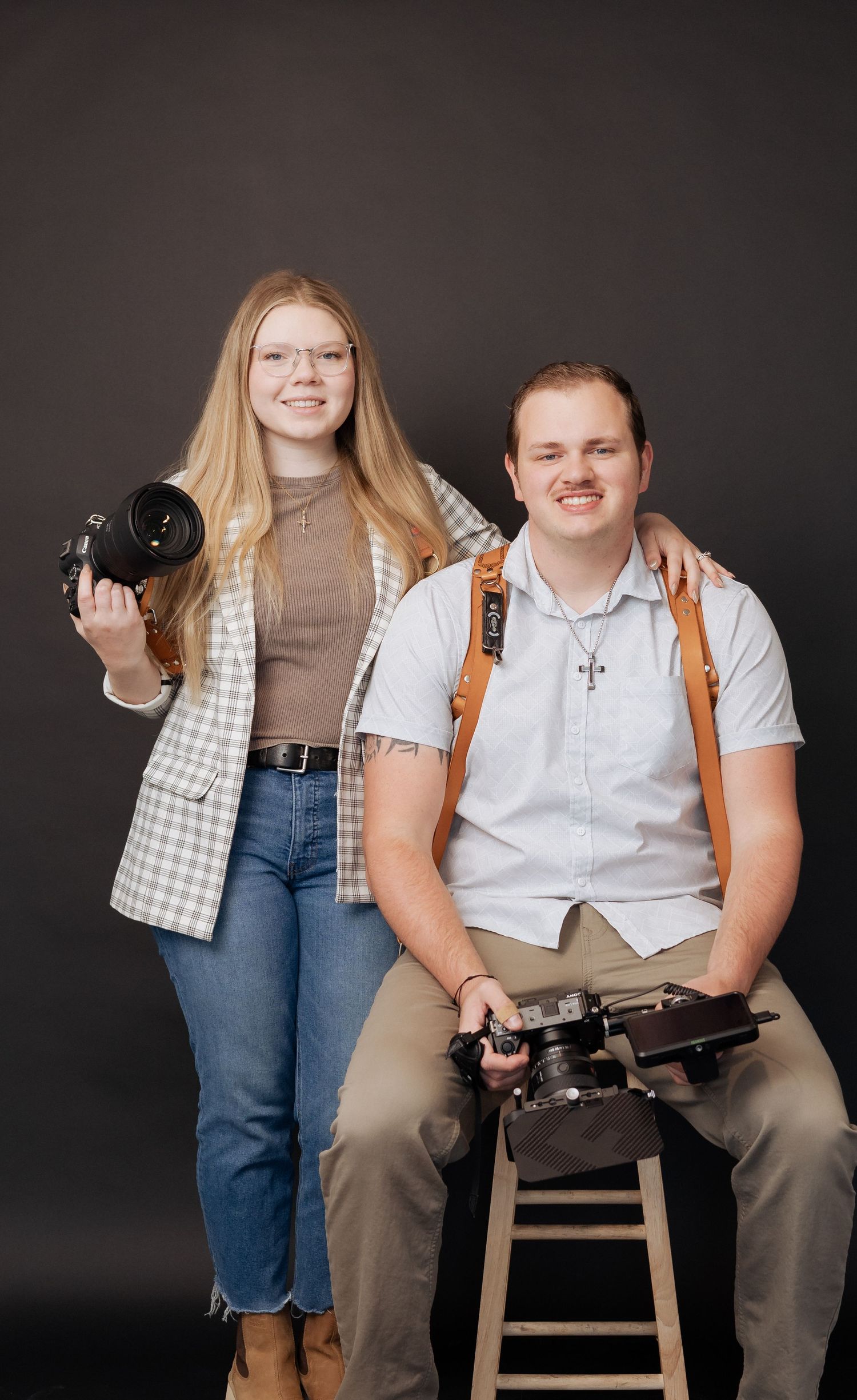 A photography team poses in a studio setting with cameras against a dark background.