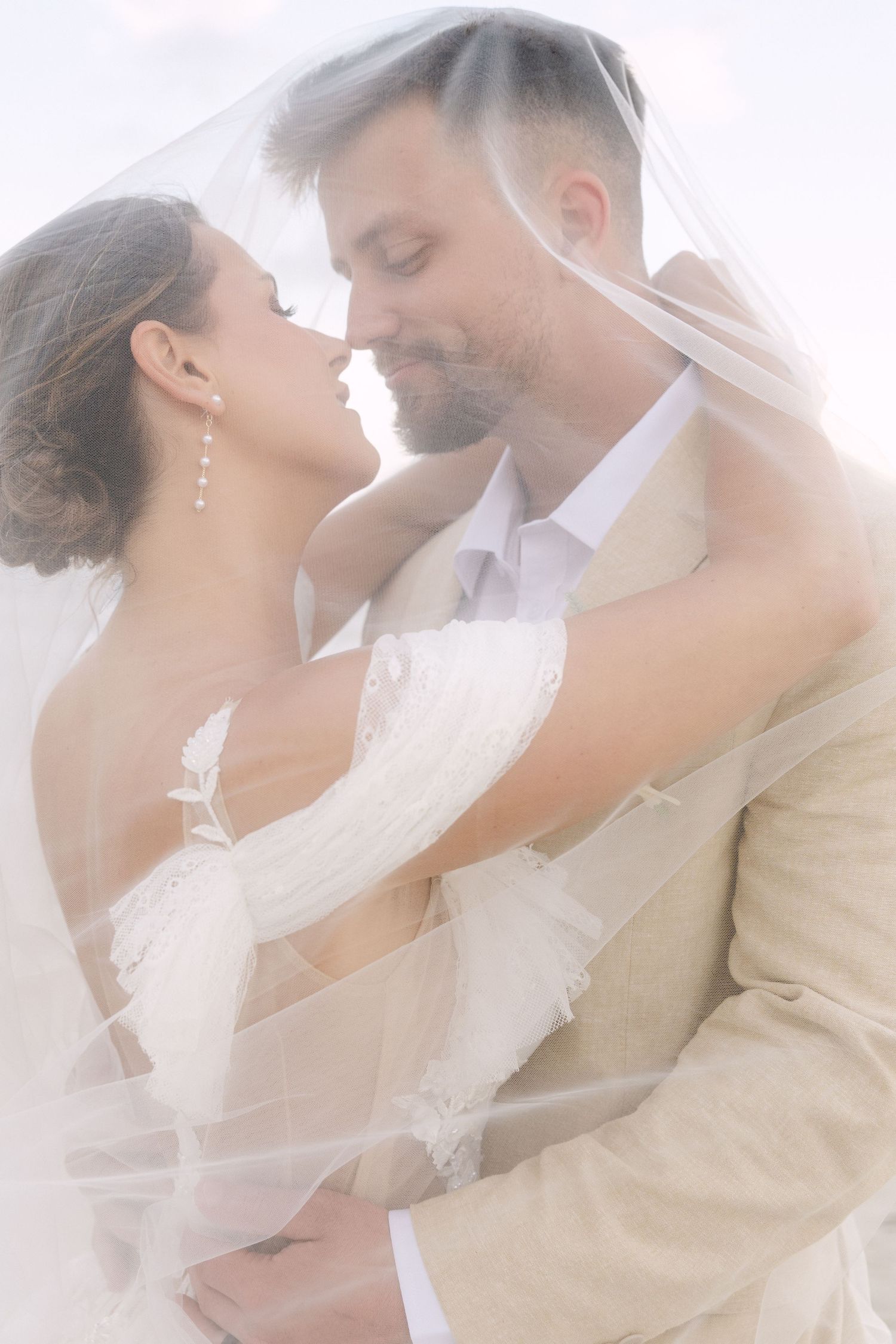 Four romantic bridal photos showing couple embracing under a delicate white veil in soft ethereal lighting.