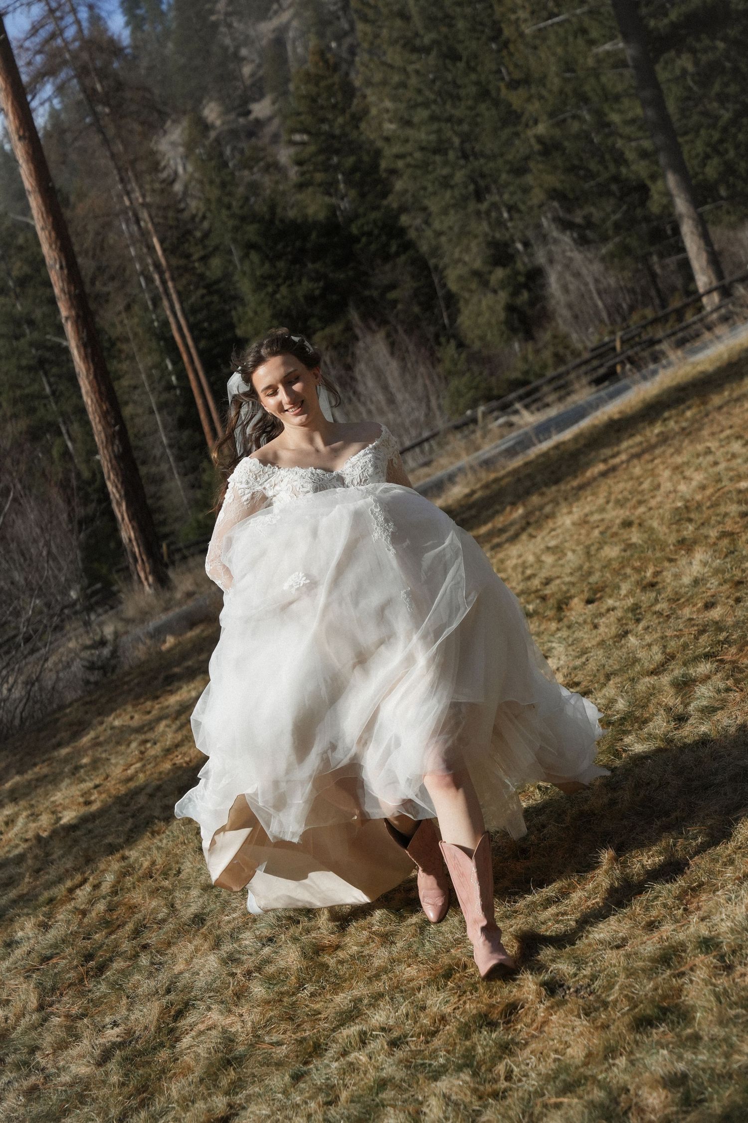 A flowing white wedding dress billows in the wind as someone runs through a forest setting.