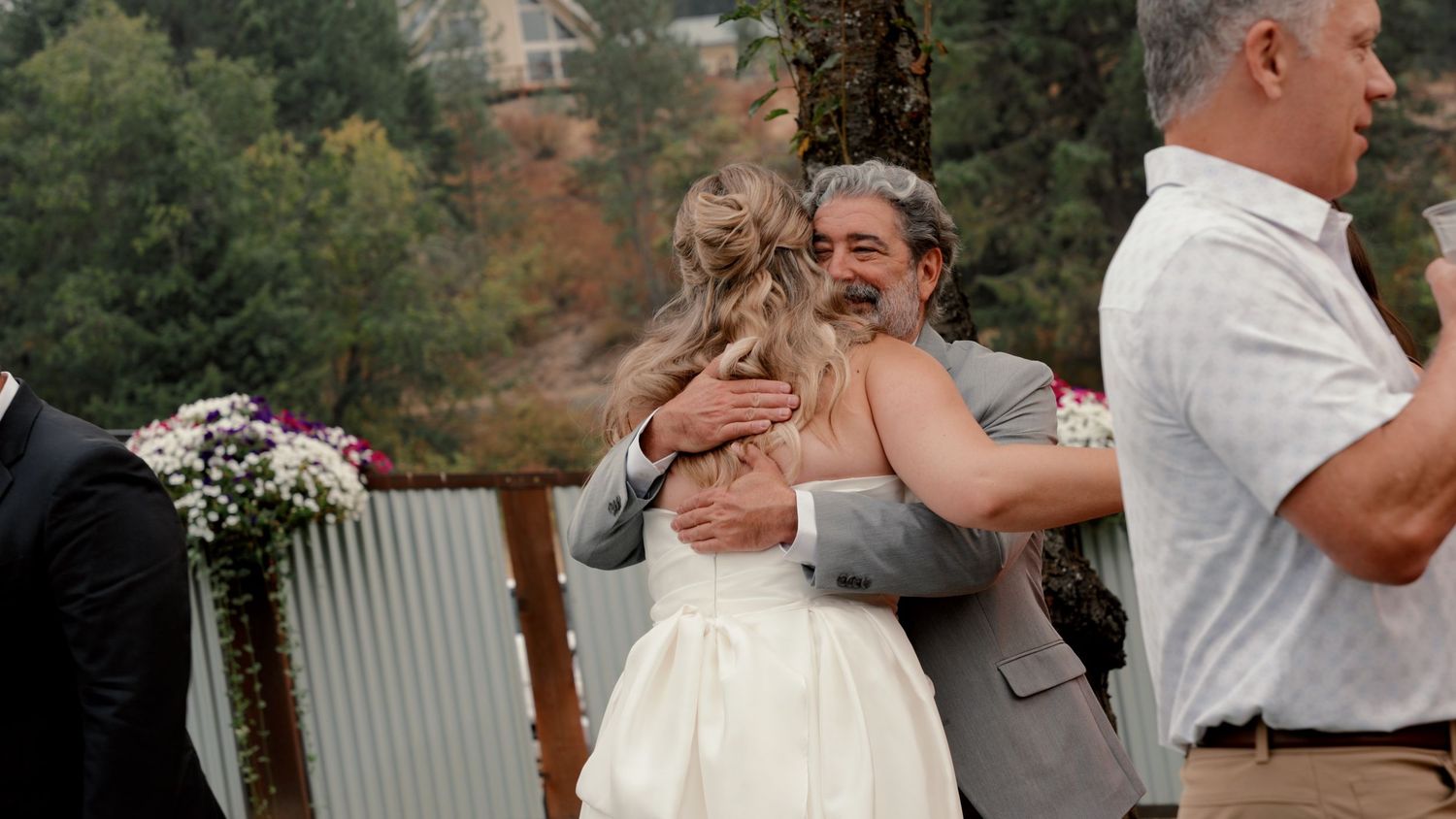 A joyful embrace between a couple at an outdoor wedding ceremony with floral decorations.