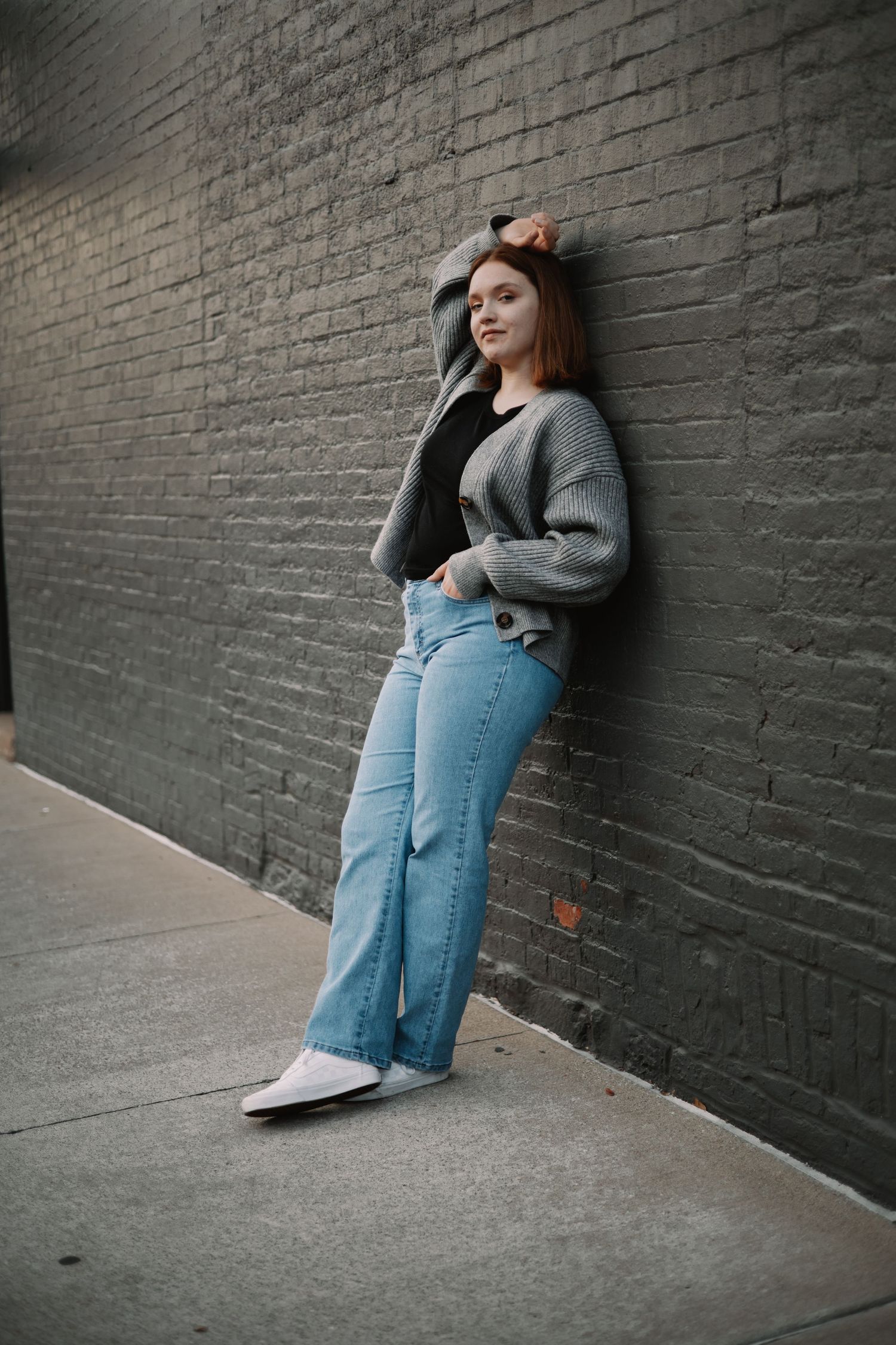 A stylized photo series showing a person in blue jeans and gray sweater reclining against a dark brick wall.