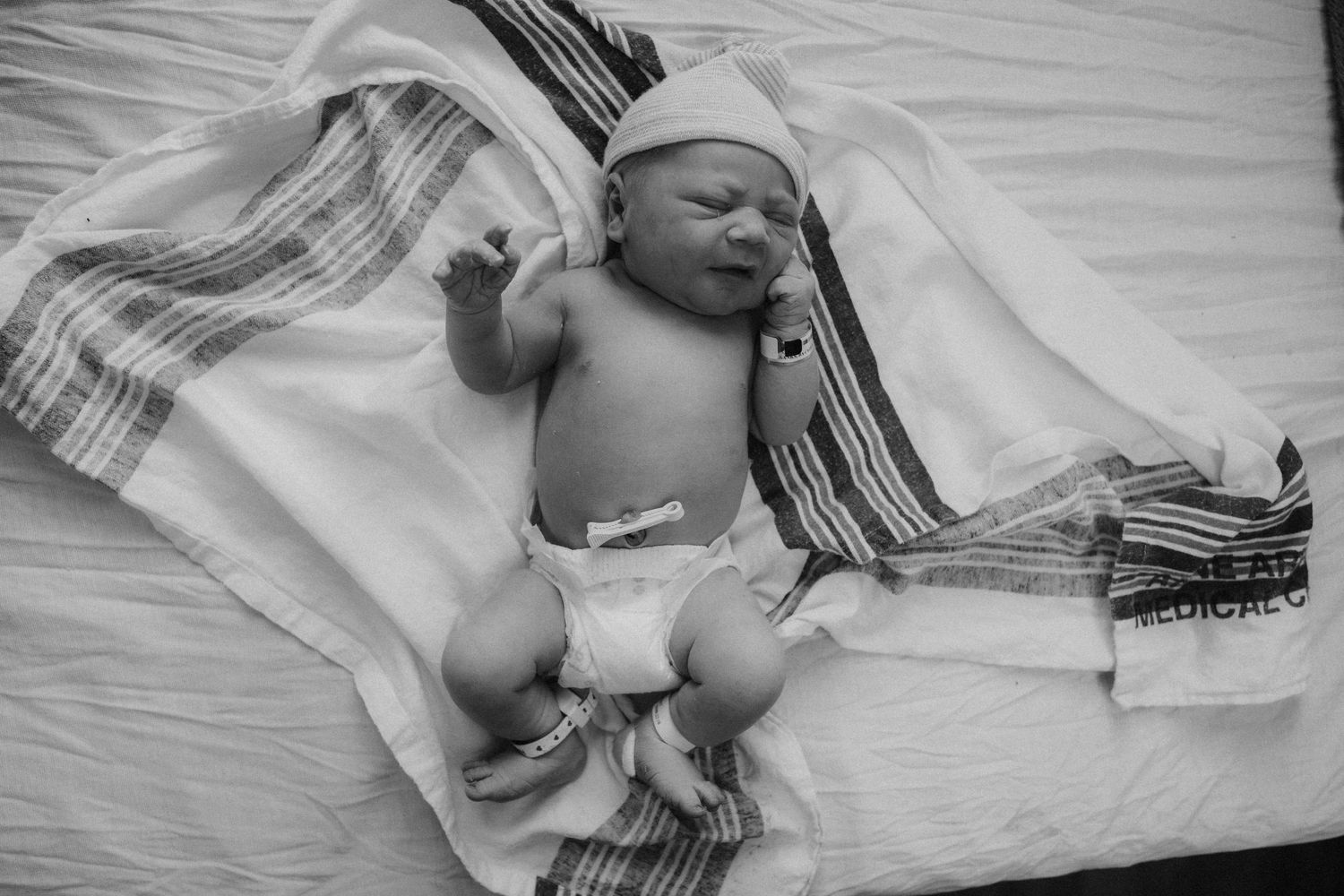 Black and white photo series showing a newborn baby lying in hospital blankets and being held after birth.