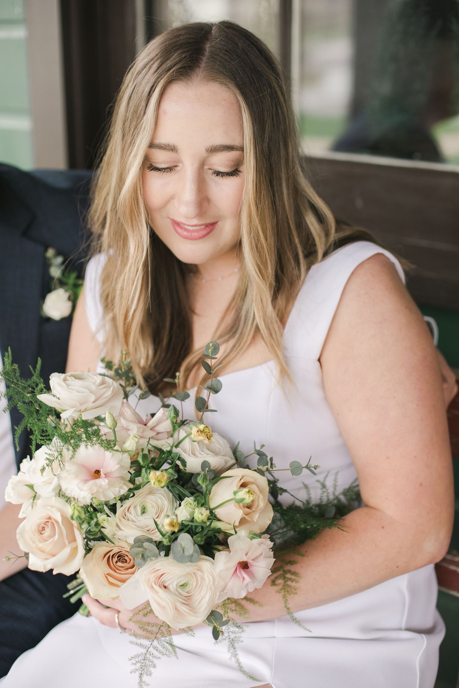 bride siting looking down at her bouqet