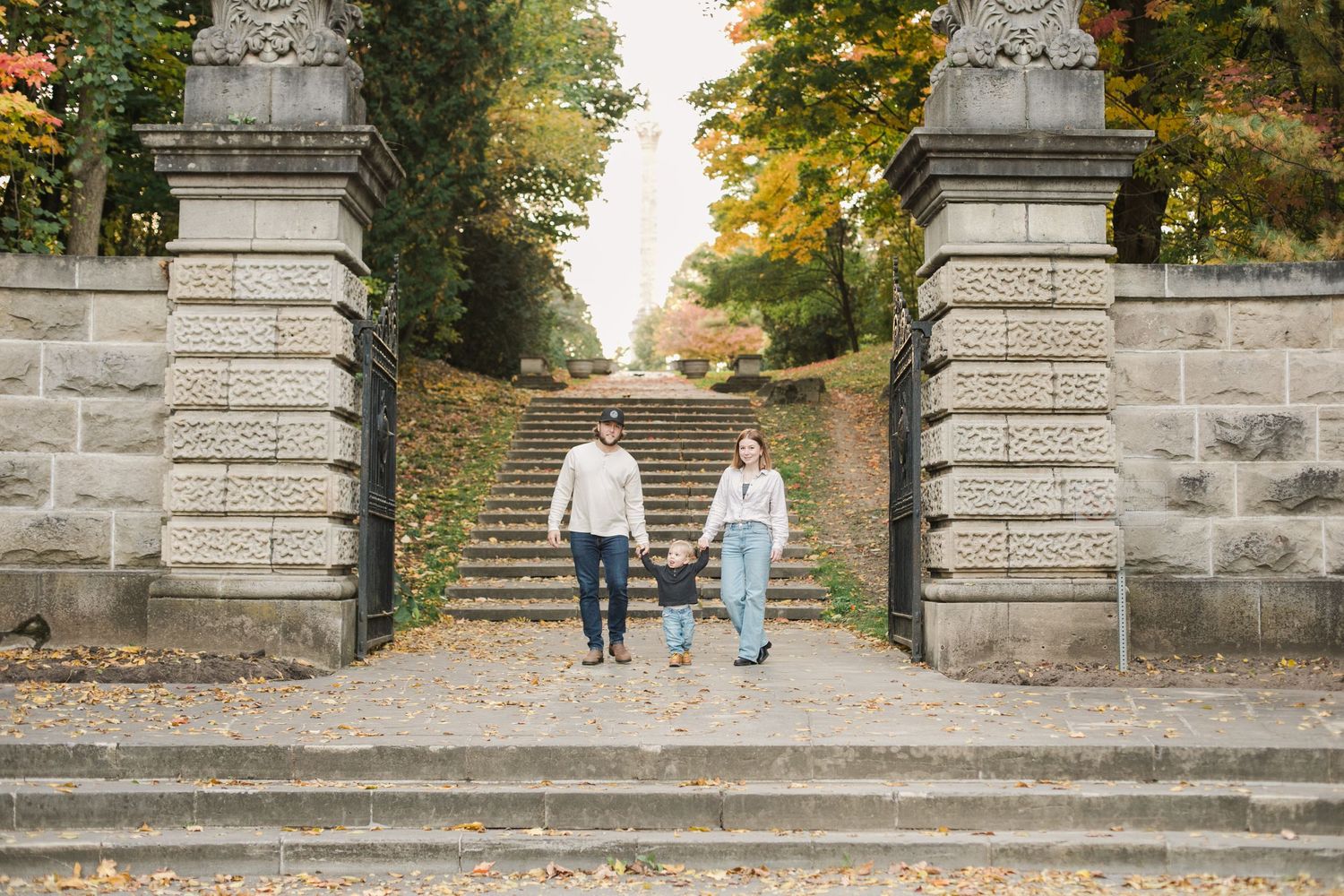 family of three holding hands and walking between the gate at Queenston heights