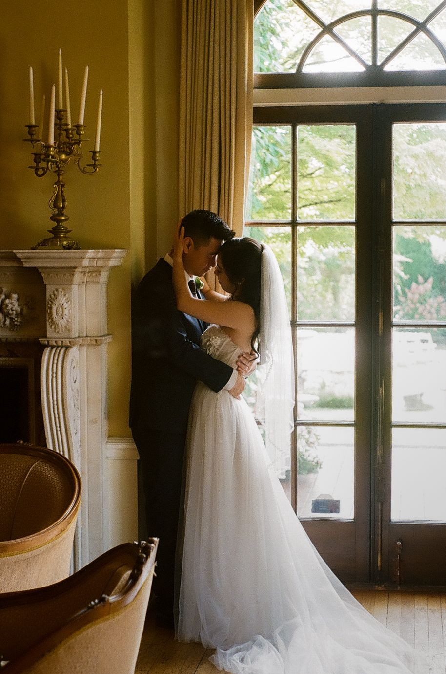 Romantic wedding scene by large arched windows with elegant curtains and candelabras.
