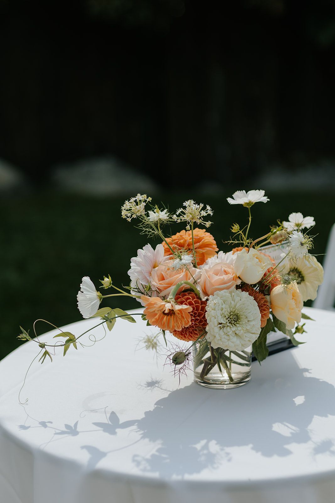 Delicate floral centerpieces with peach and white blooms arranged on a white tablecloth.