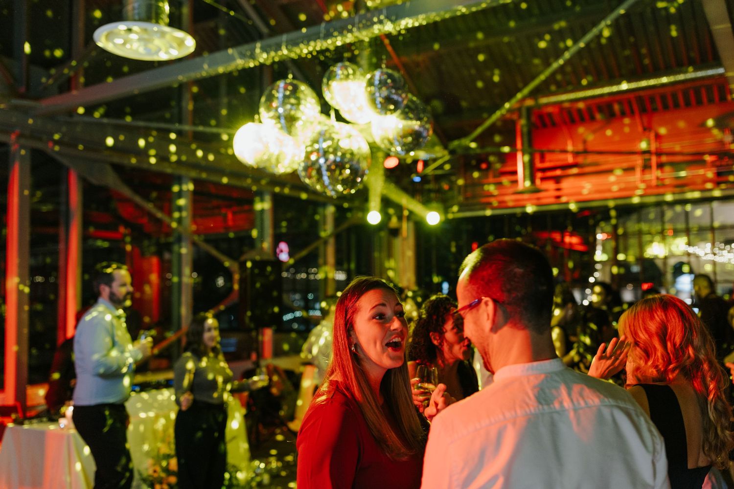 Wedding reception dance floor illuminated with warm string lights and disco ball effects.