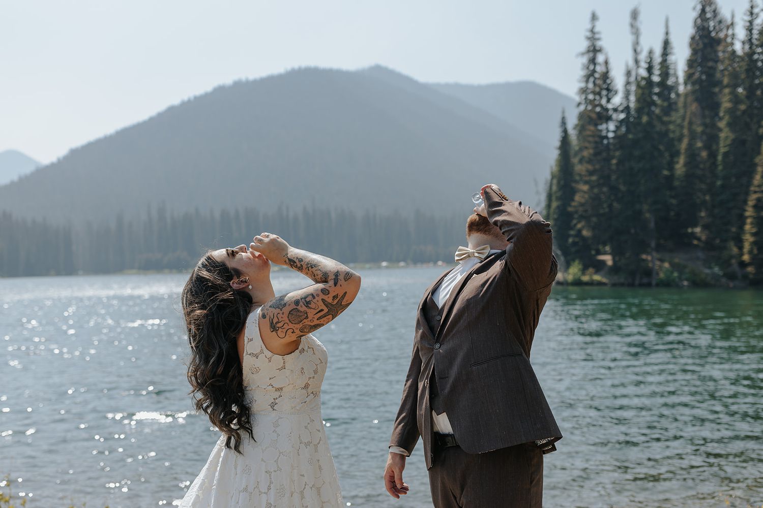 Couple embracing by a scenic mountain lake during their wedding photoshoot.