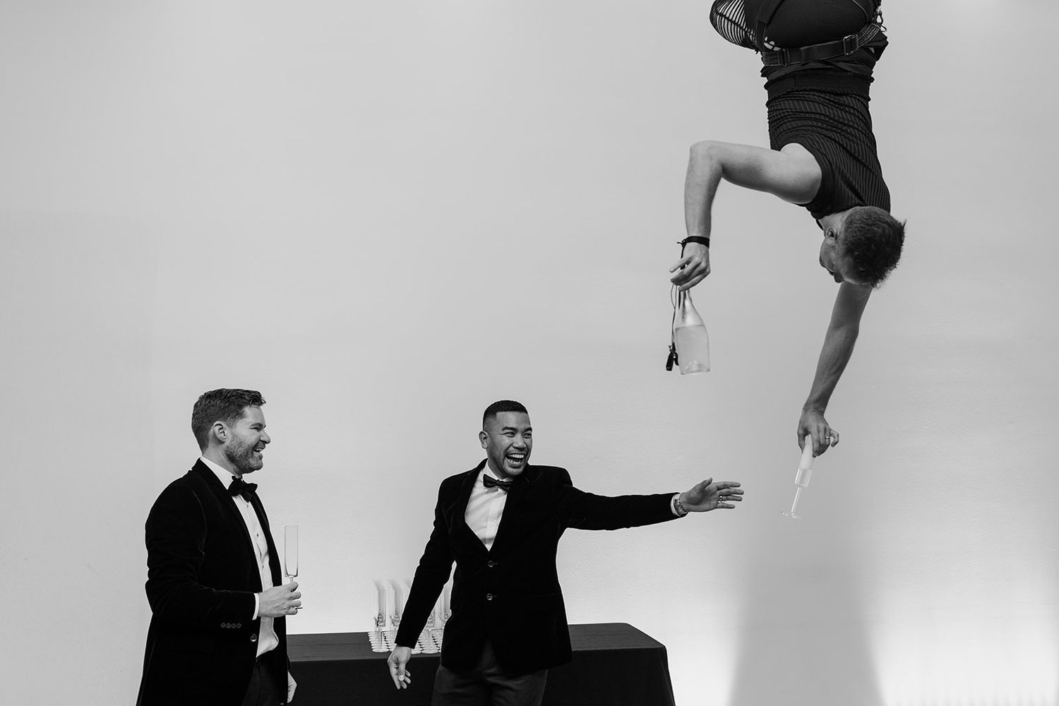 Black and white photo of groomsmen jumping and posing against a plain background.