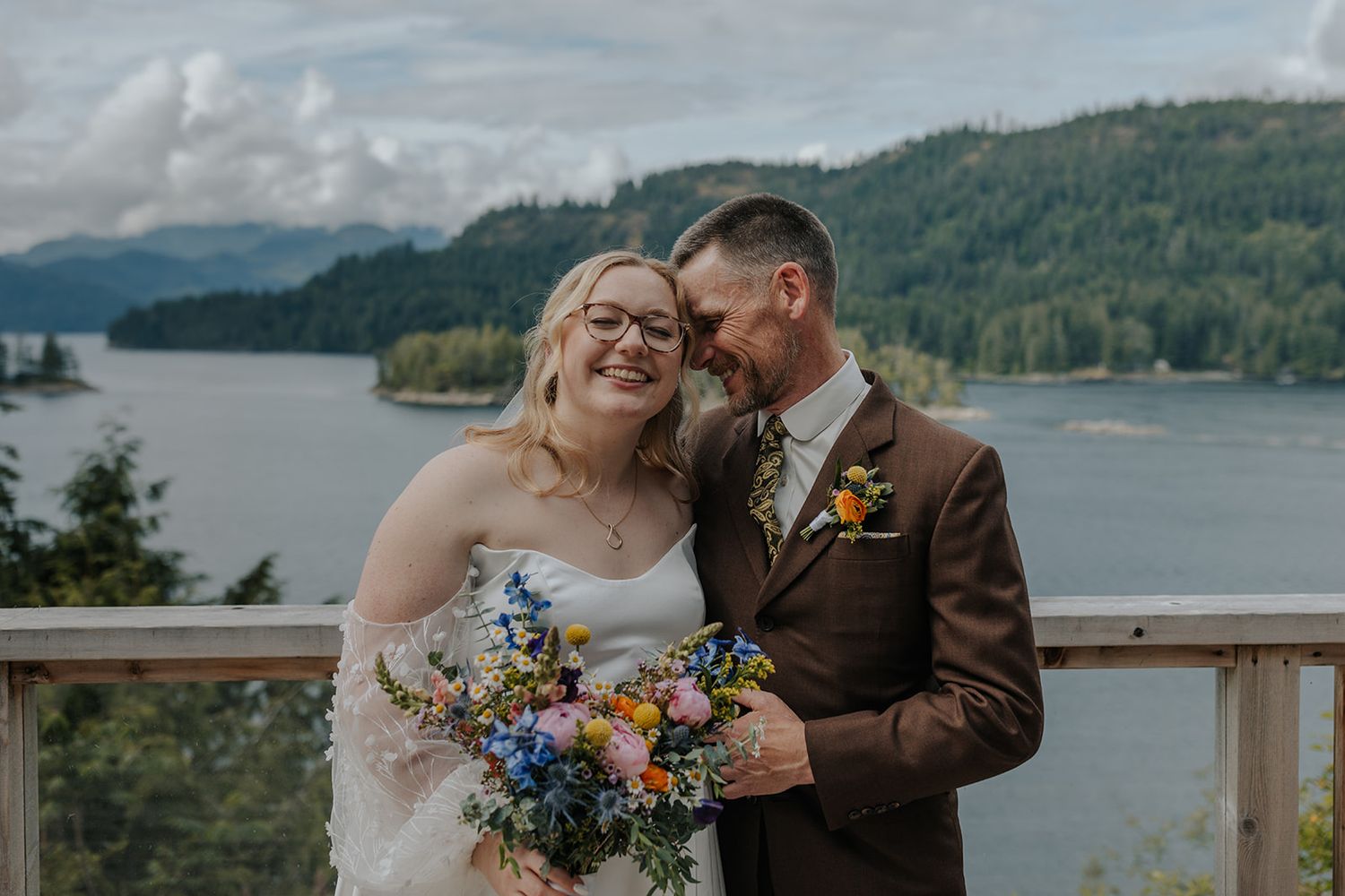 Candid wedding celebration photos on outdoor viewing deck with mountainous backdrop.