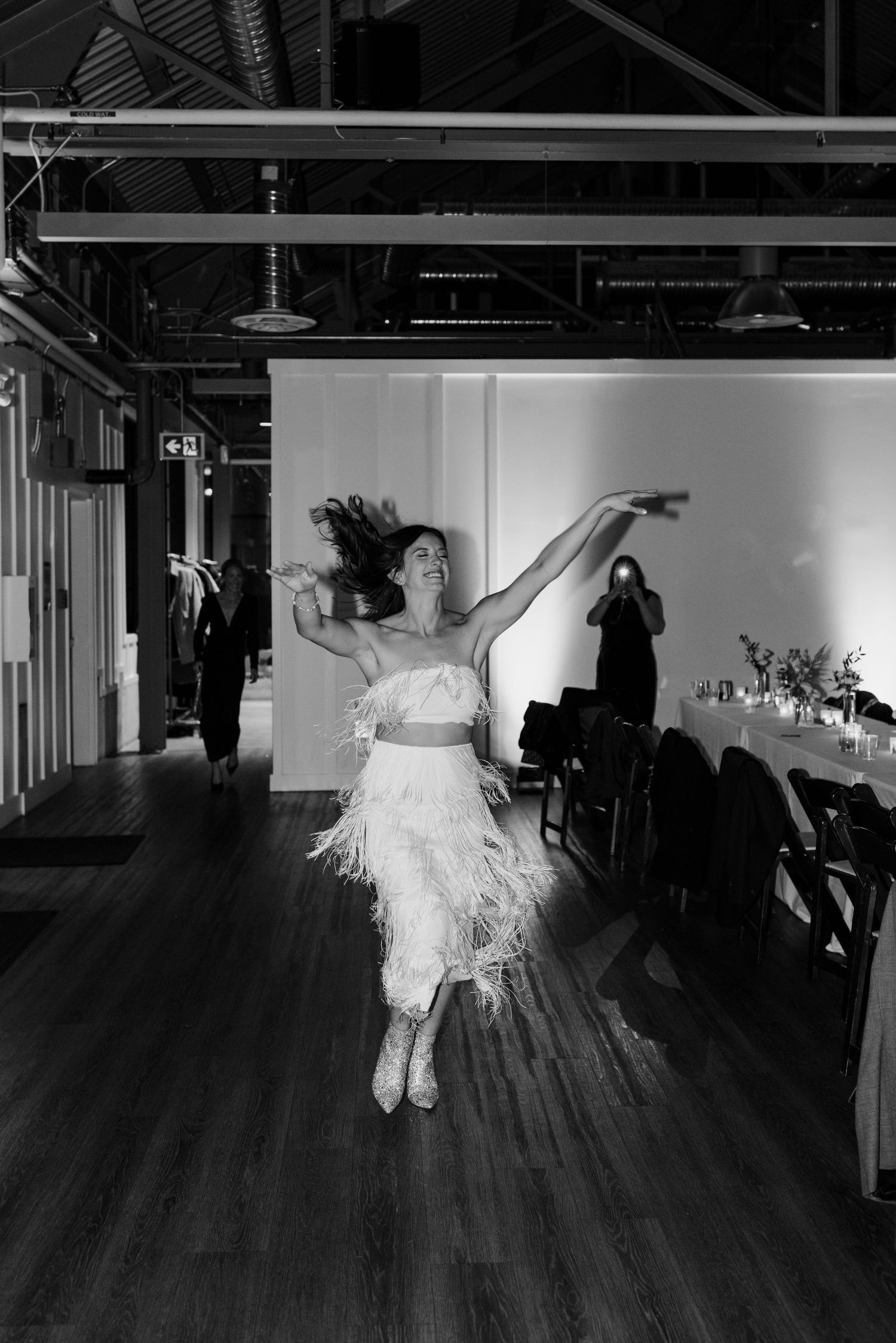 Black and white sequence shows someone in a white dress jumping across a dark room.