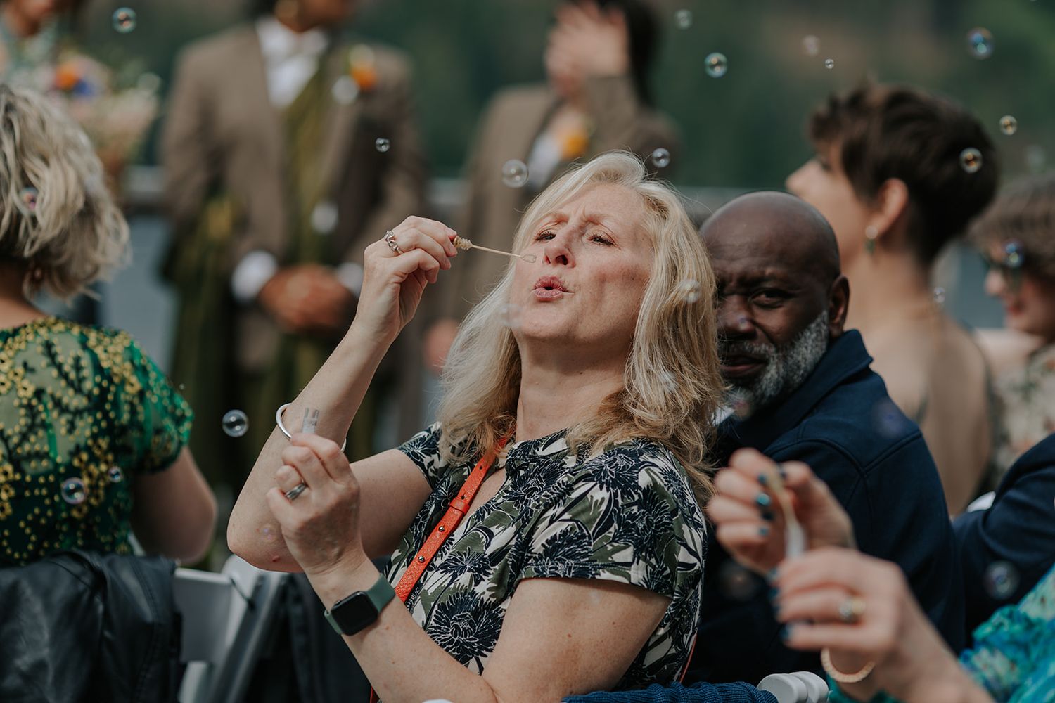Wedding guests blow bubbles during outdoor reception festivities.