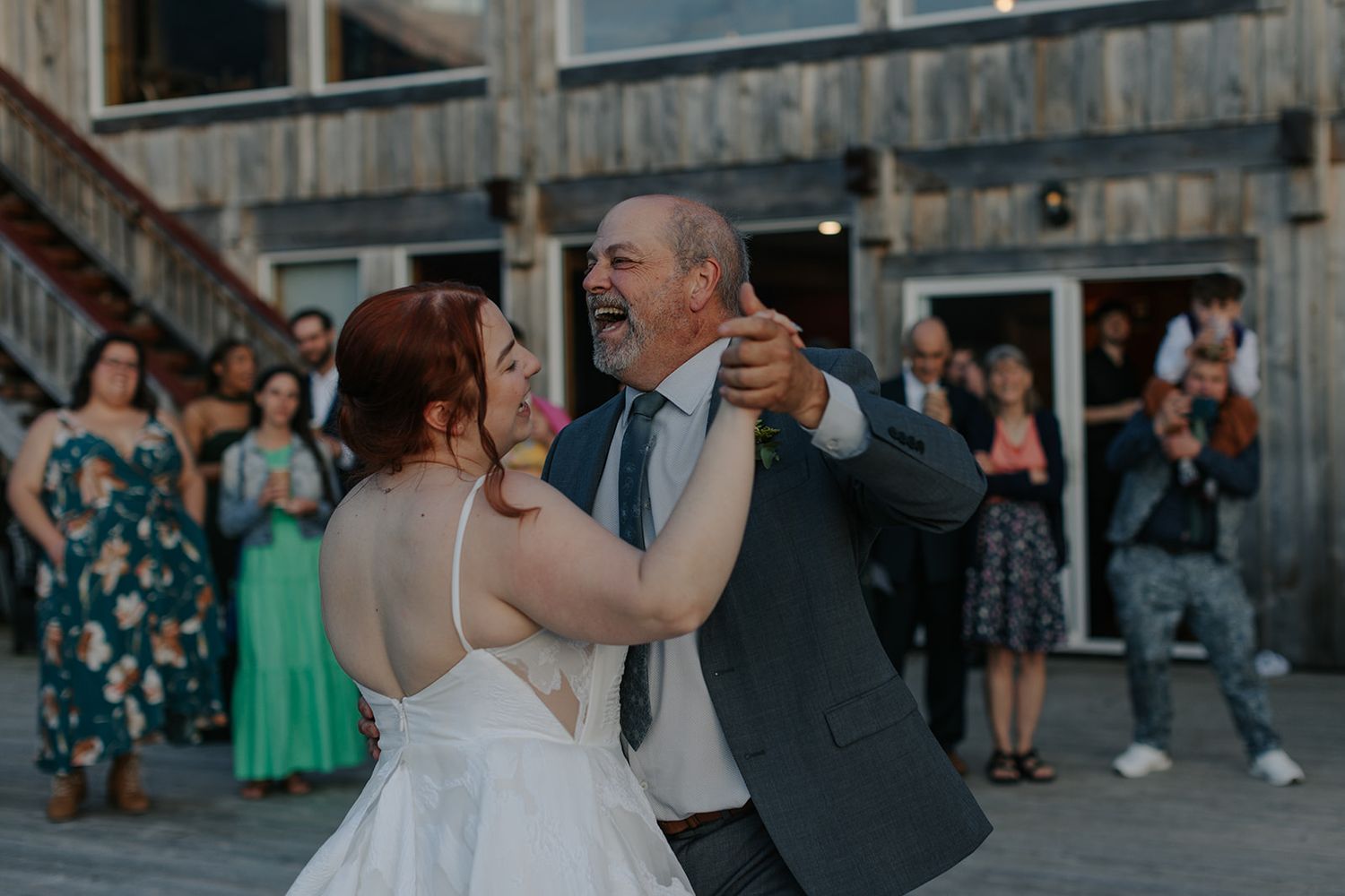 Wedding celebration on a rustic wooden deck with mountains in the background.