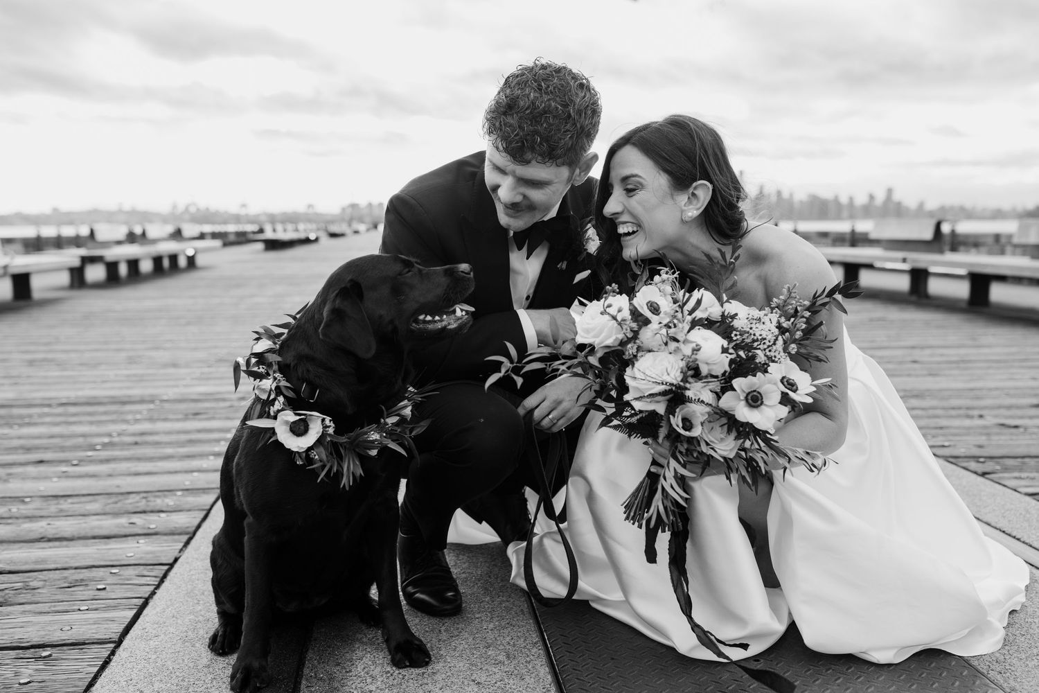 Wedding couple shares intimate moments on a waterfront deck during an overcast day.