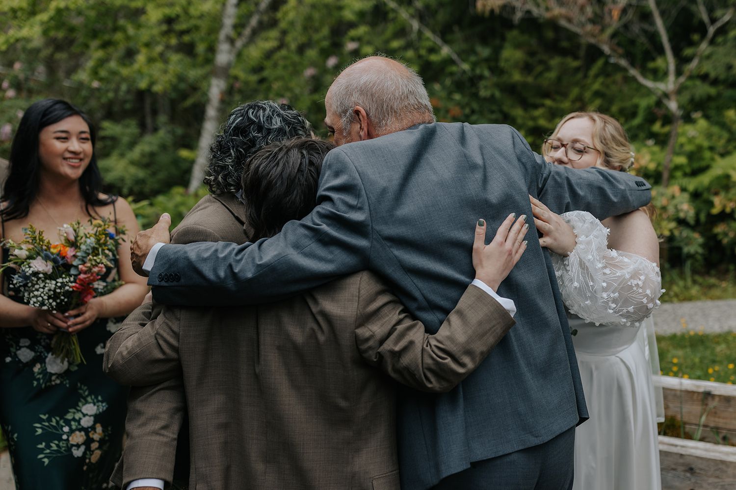 Wedding guests embracing during outdoor celebration on wooden deck.