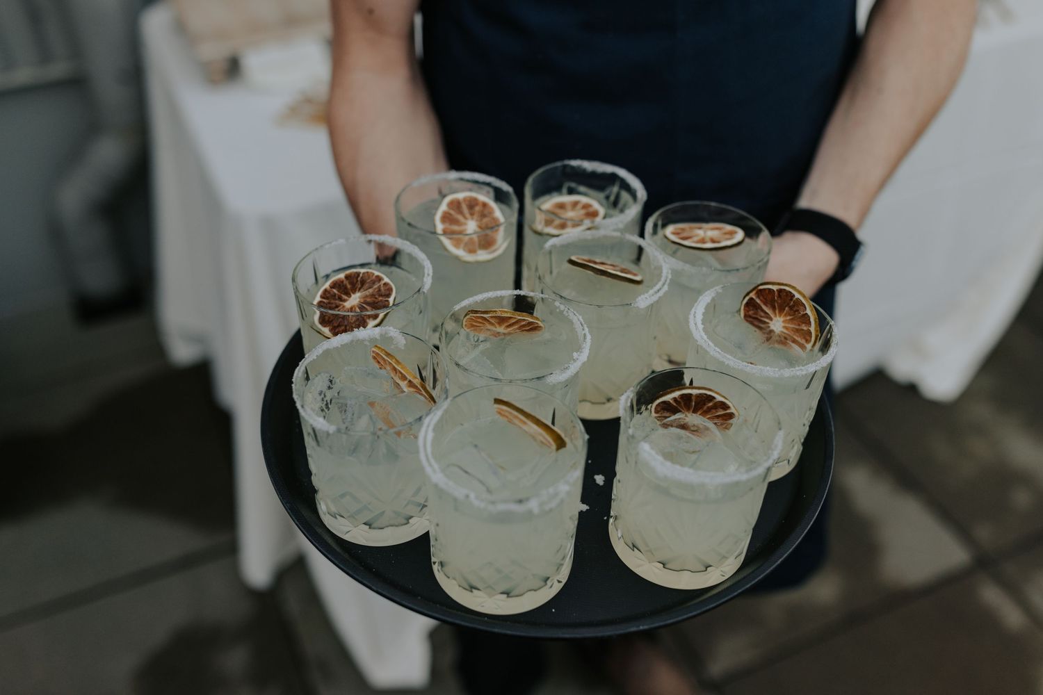 Tray of garnished cocktails being served at elegant wedding reception.