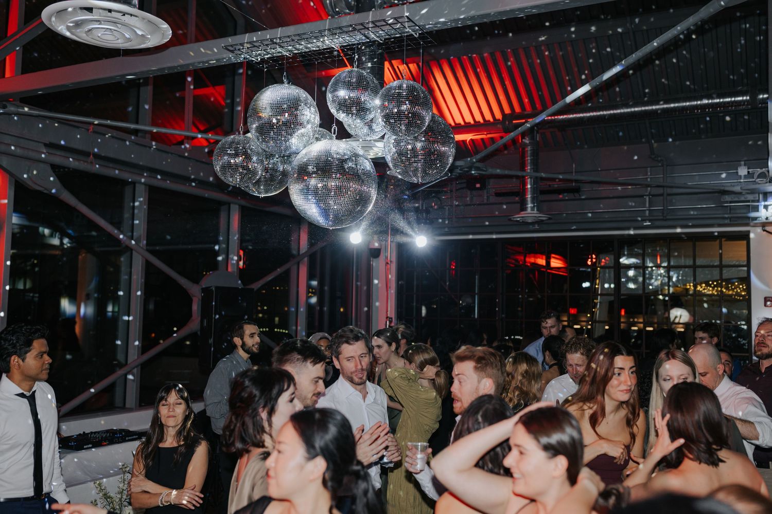 Crowded nightclub scene with people dancing under disco lights and red ambient lighting.