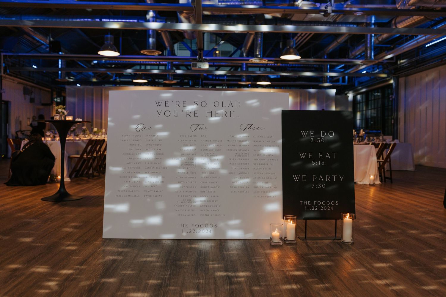 Modern wedding reception setup with projected lights and a welcome sign in an industrial venue.