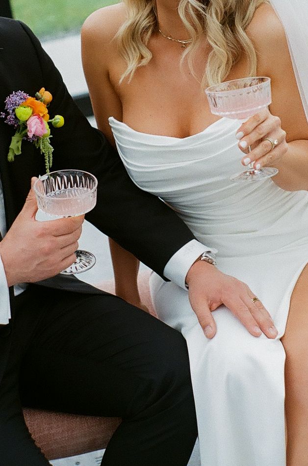 Close-up of wedding couple holding crystal glasses during celebration.