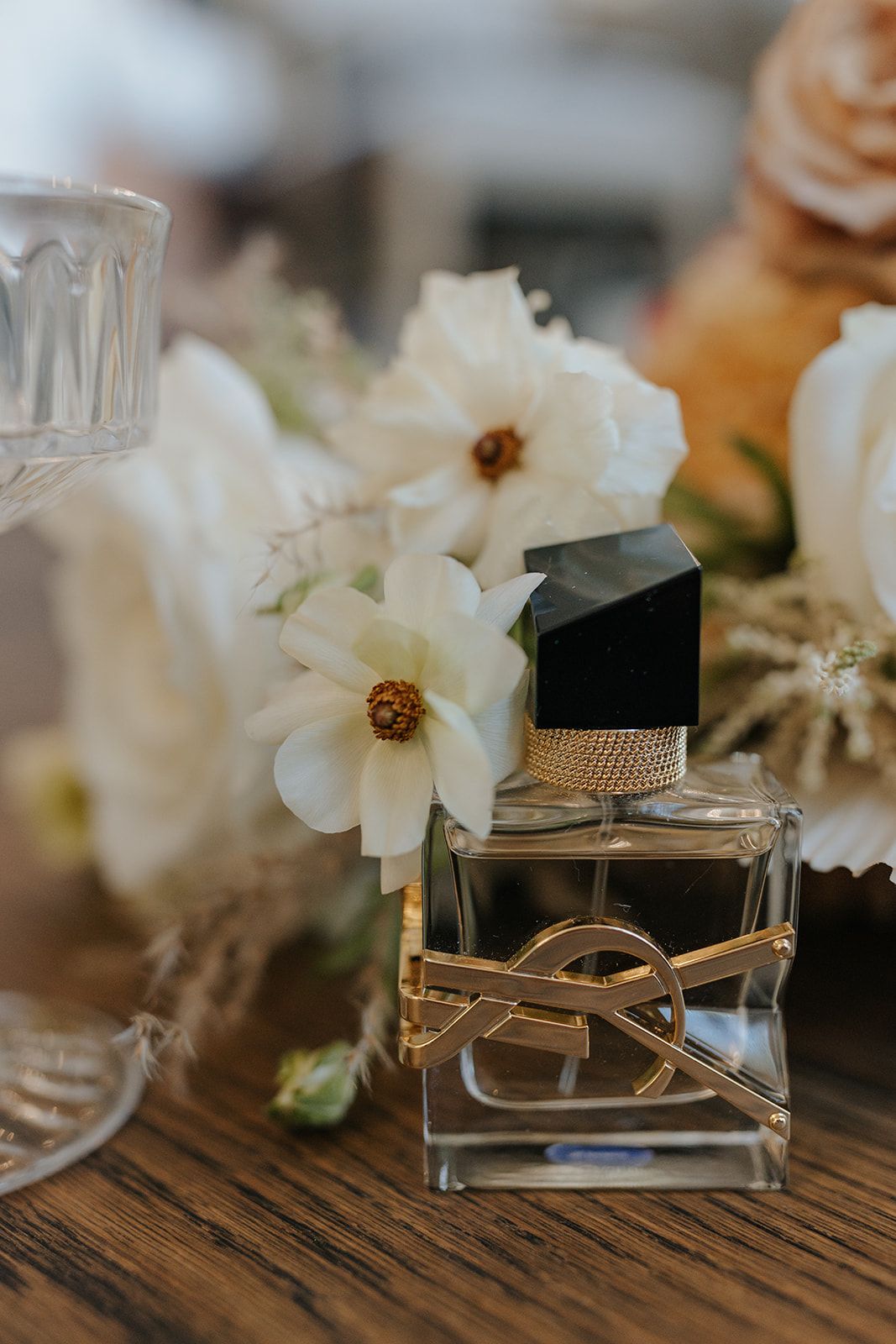 Elegant perfume bottles and white flowers arranged on rustic wooden surface.