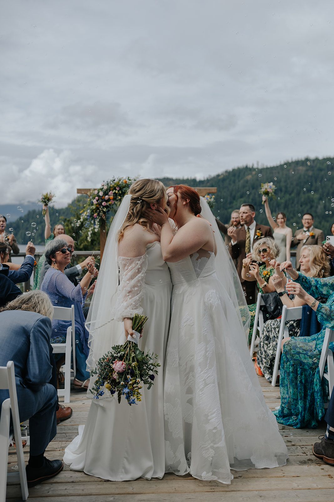 Wedding ceremony on a scenic mountain dock with floral arch and seated guests.