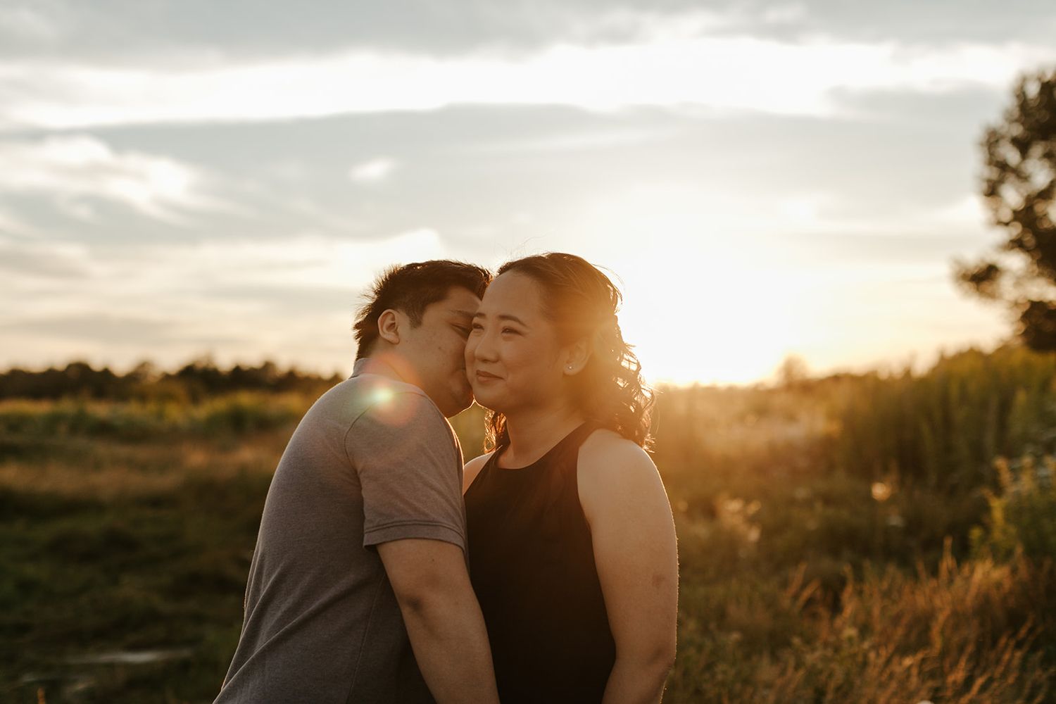 A romantic sunset moment between two people in a natural outdoor setting.