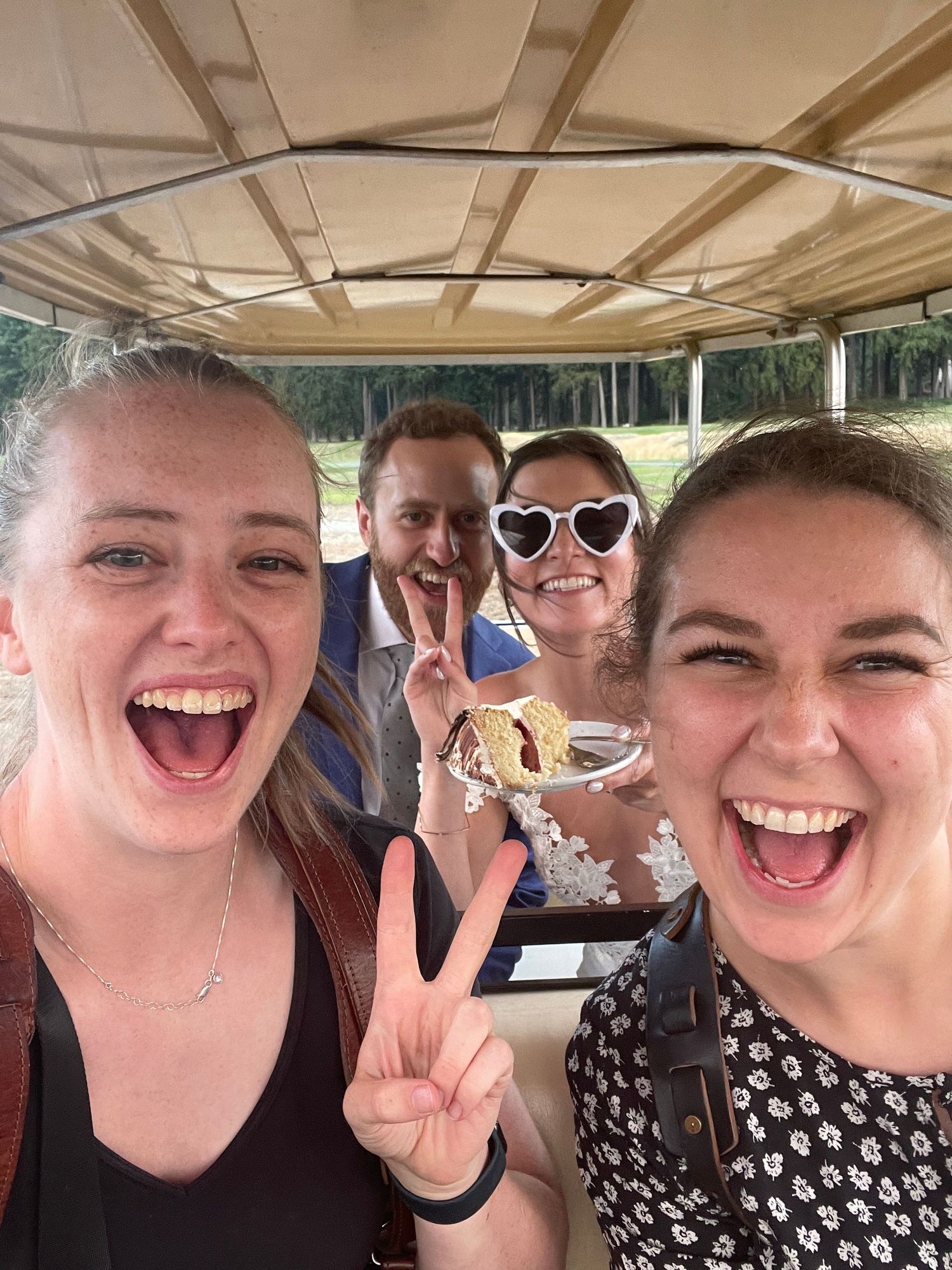 Group of friends laughing and making peace signs while riding in a vehicle together.