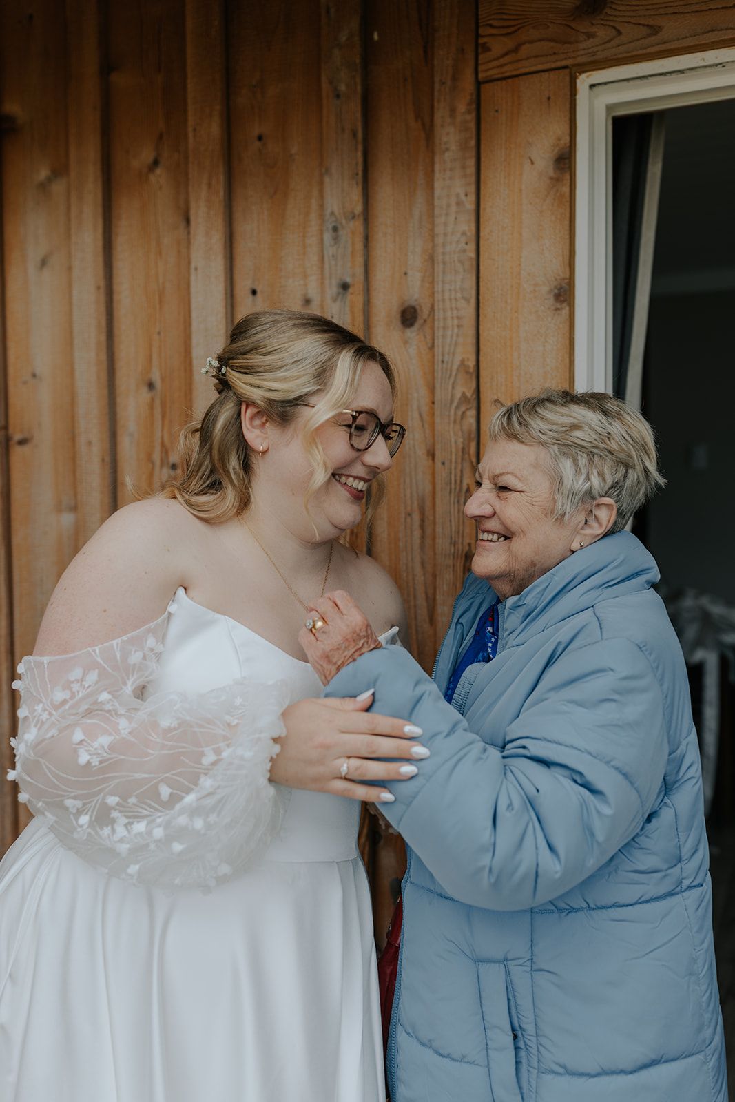 A tender moment shared between two people in white dress and blue jacket on a wooden porch.