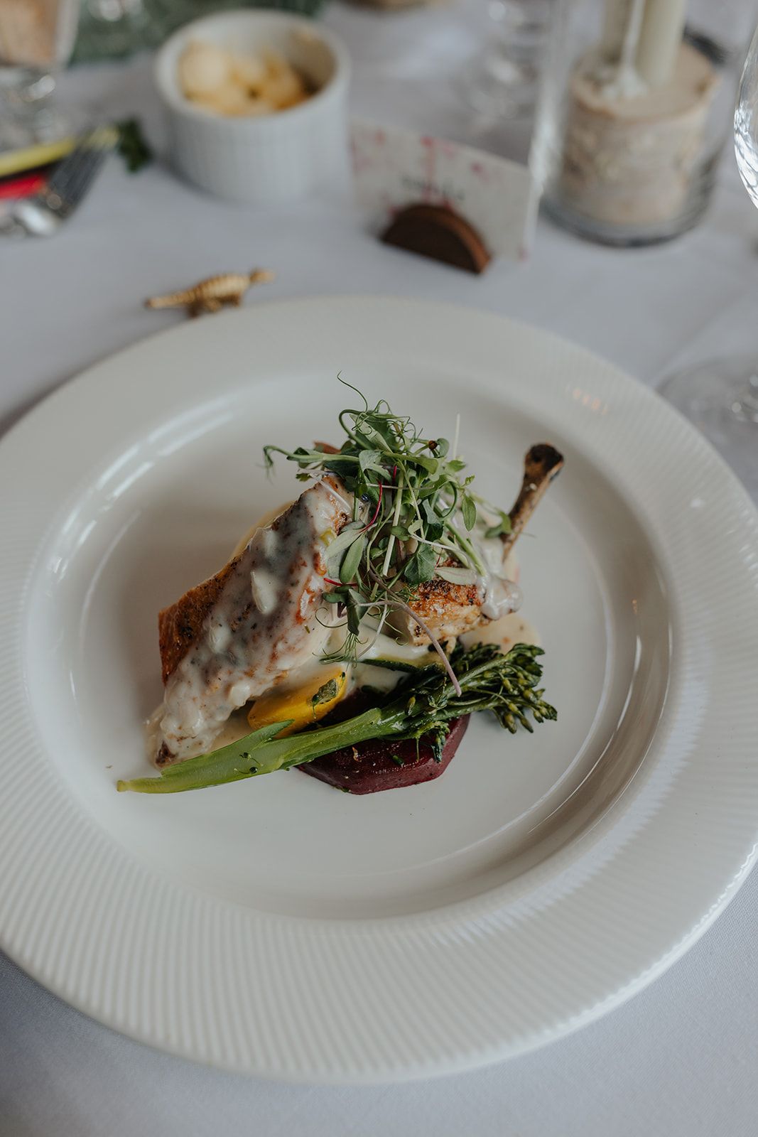 Elegant plated fish dish with microgreens and vegetables on white ceramic plates.
