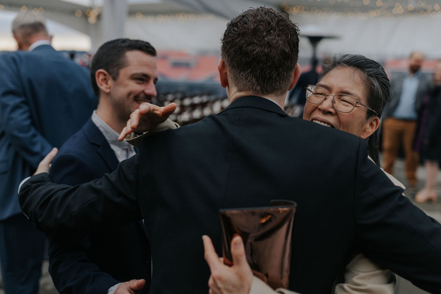 Wedding party members embrace in a group hug during outdoor celebrations.