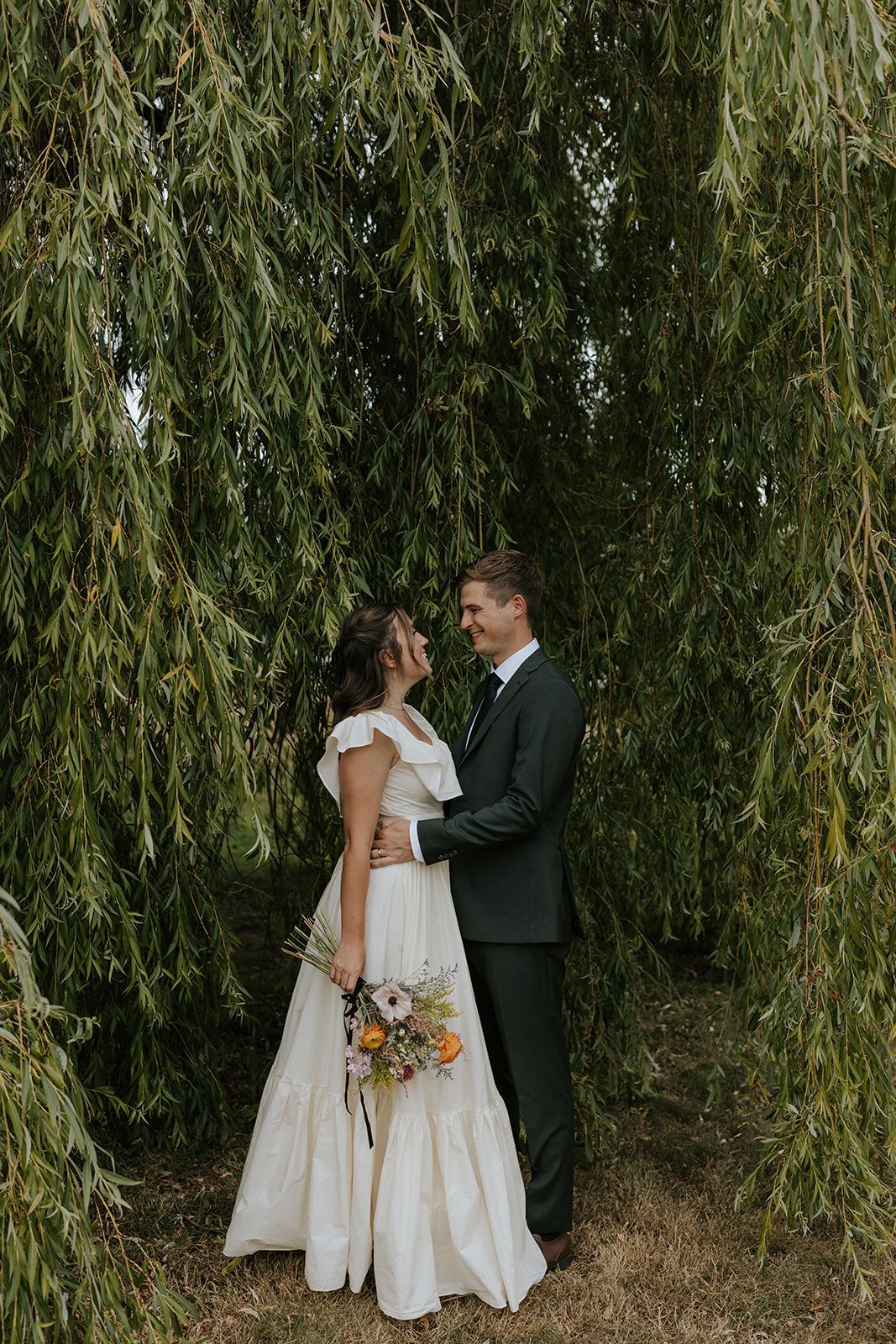 Romantic wedding portraits under drooping willow tree branches.