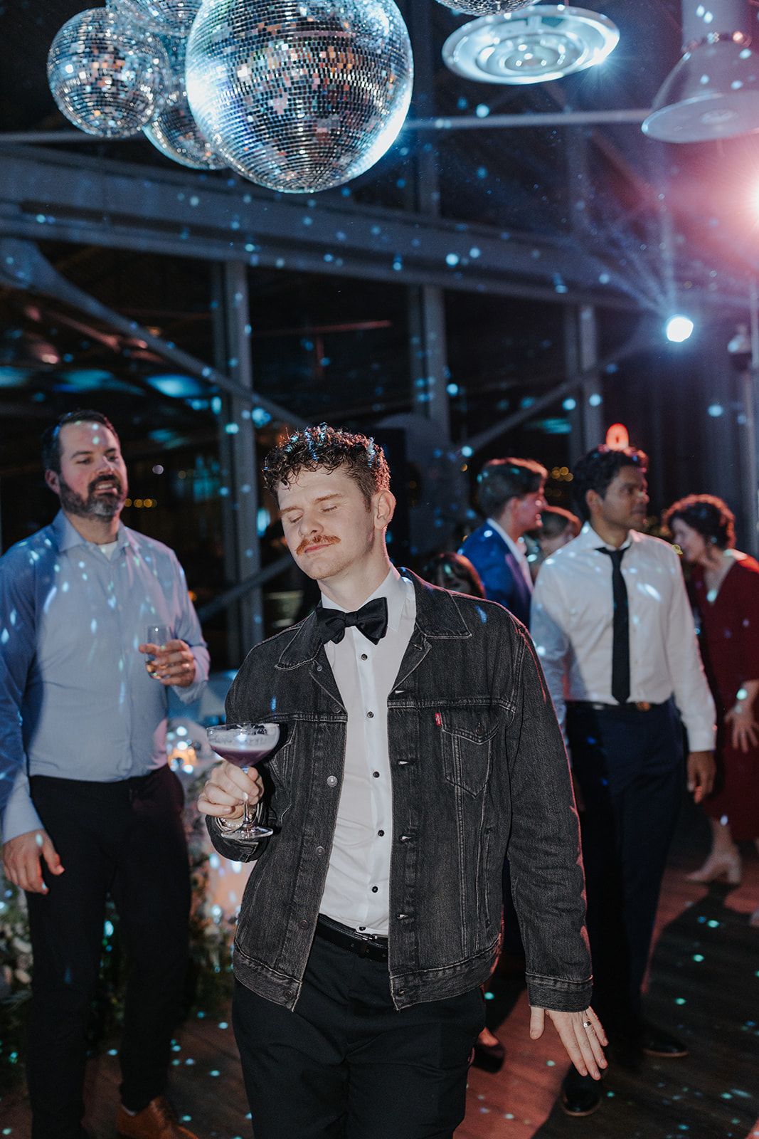 Wedding reception dance party under disco balls with moody blue lighting.