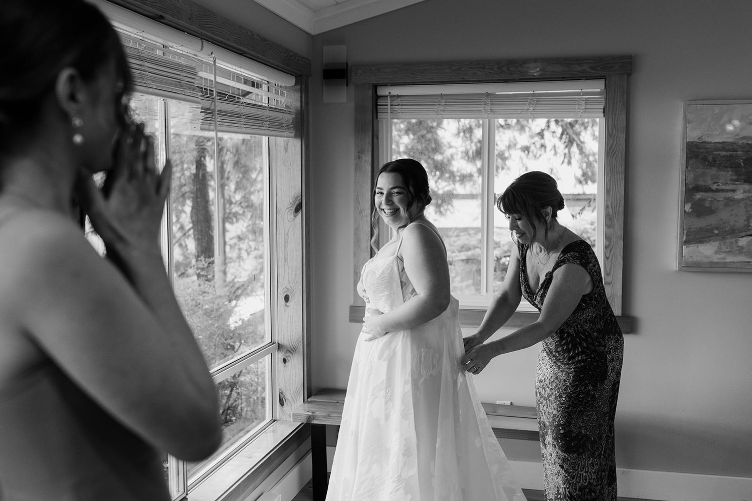 Wedding preparation scene in a bright room with white dress adjustments being made.