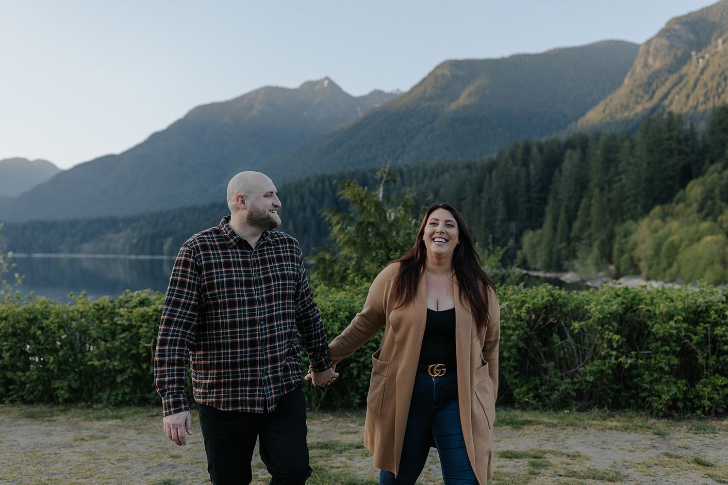 A romantic couple walking along a scenic mountain vista during golden hour.