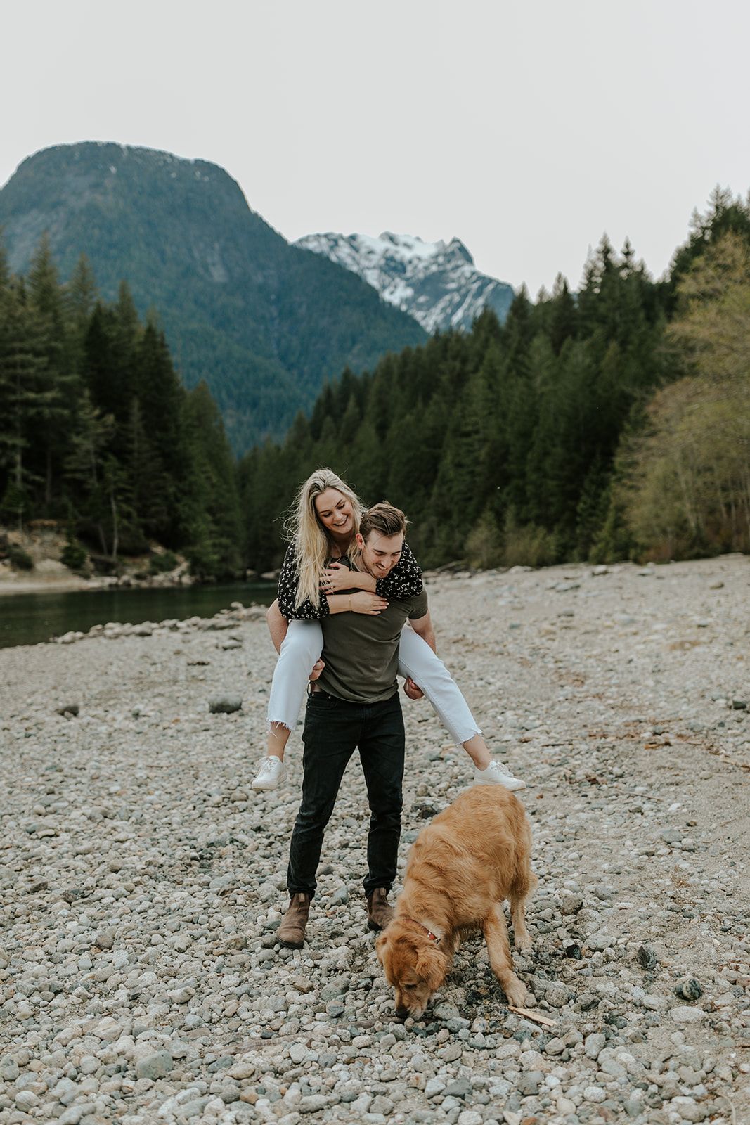 A couple walks with their golden retriever on a rocky mountain trail.