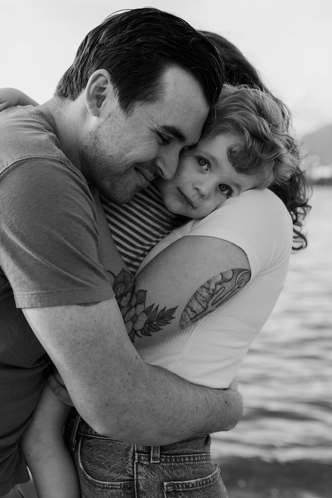 Intimate black and white photos of couple embracing by the water.