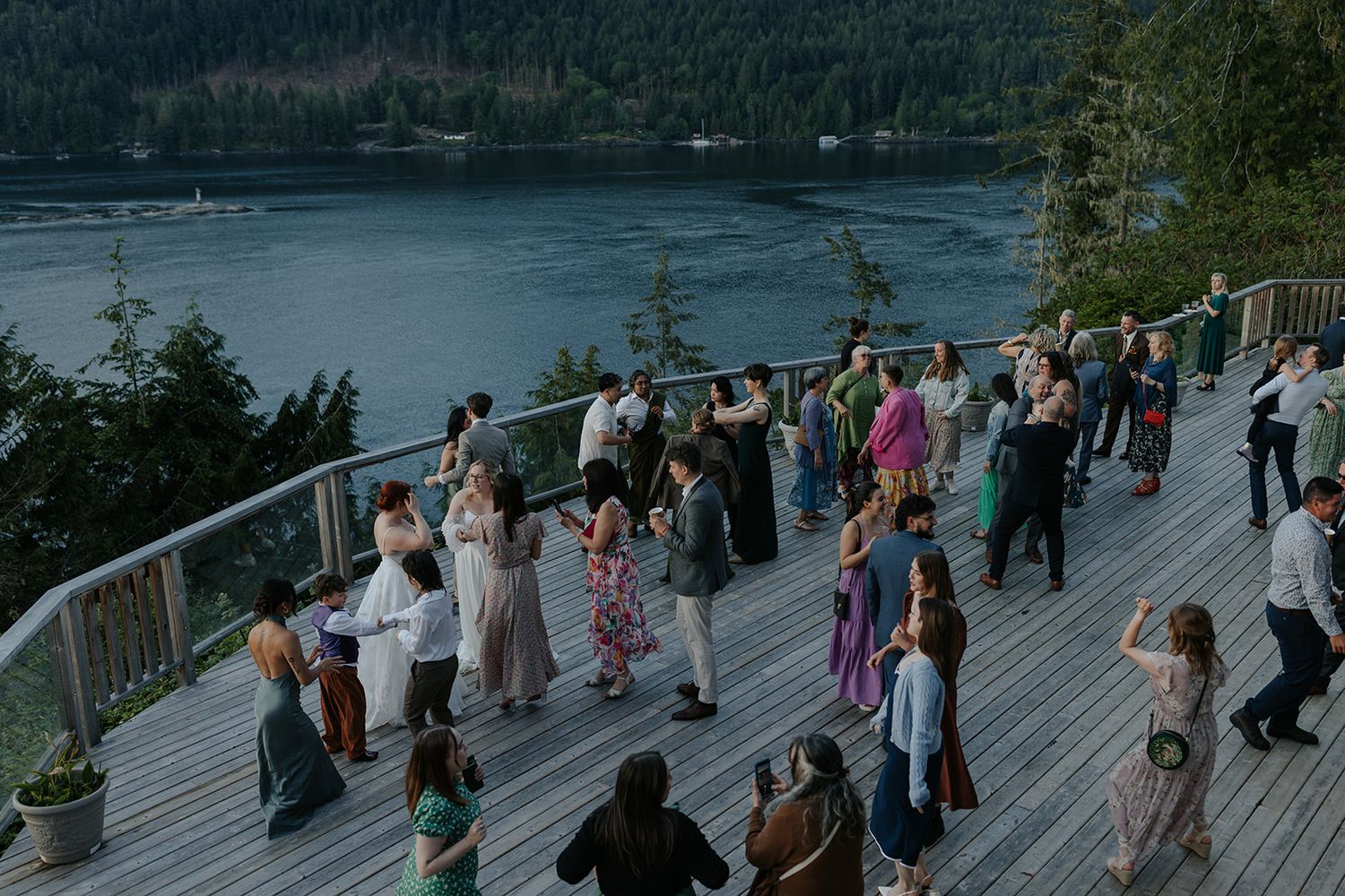 Guests gather on a scenic waterfront deck during an evening celebration.