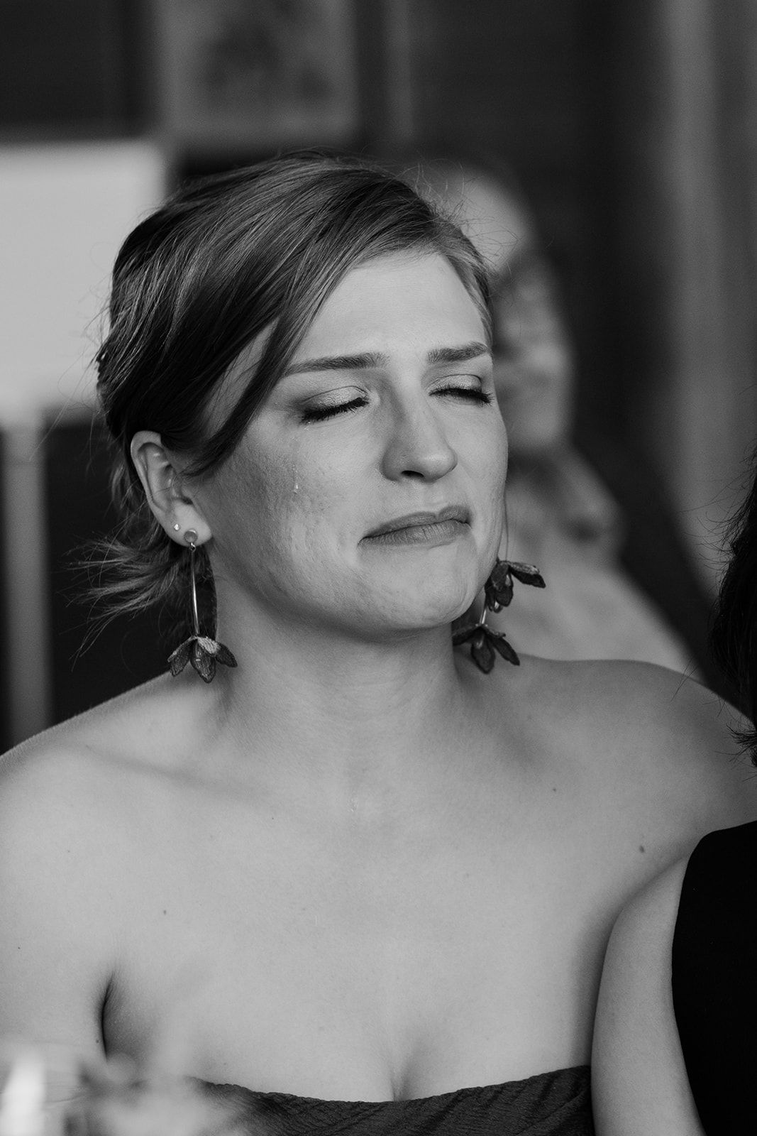 Black and white portrait of guest with dangling earrings at formal event.