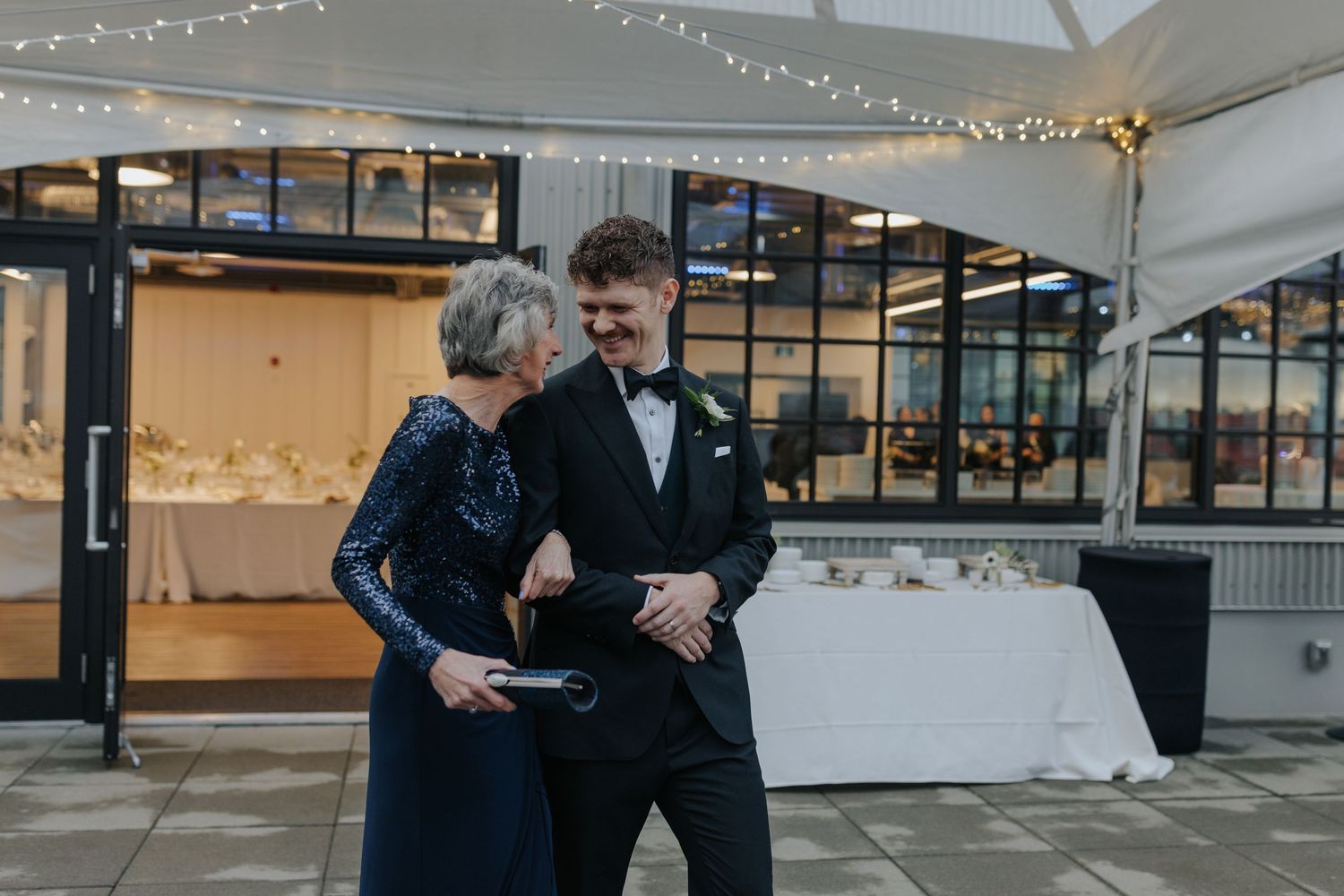 A tender moment shared between guests during an indoor wedding reception with string lights.