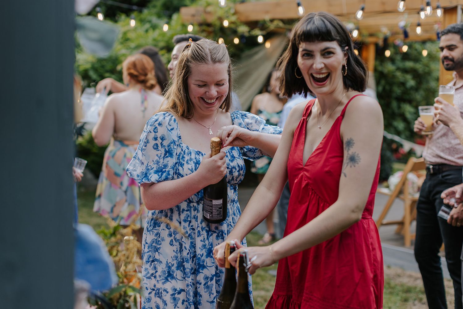 Wedding guests dance and celebrate outdoors under string lights at reception.