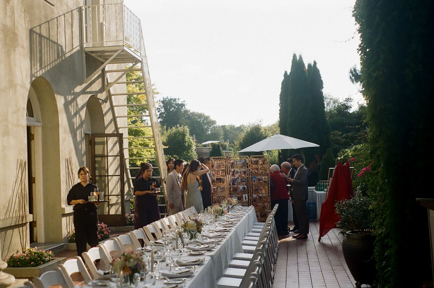 Long outdoor wedding reception table setup with white linens and natural decor.
