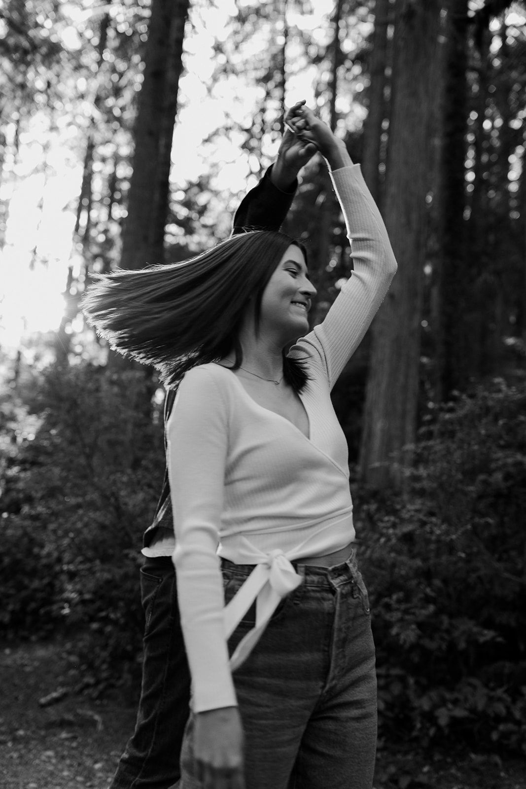 A joyful moment captured in a forest setting with dancing and movement in black and white.