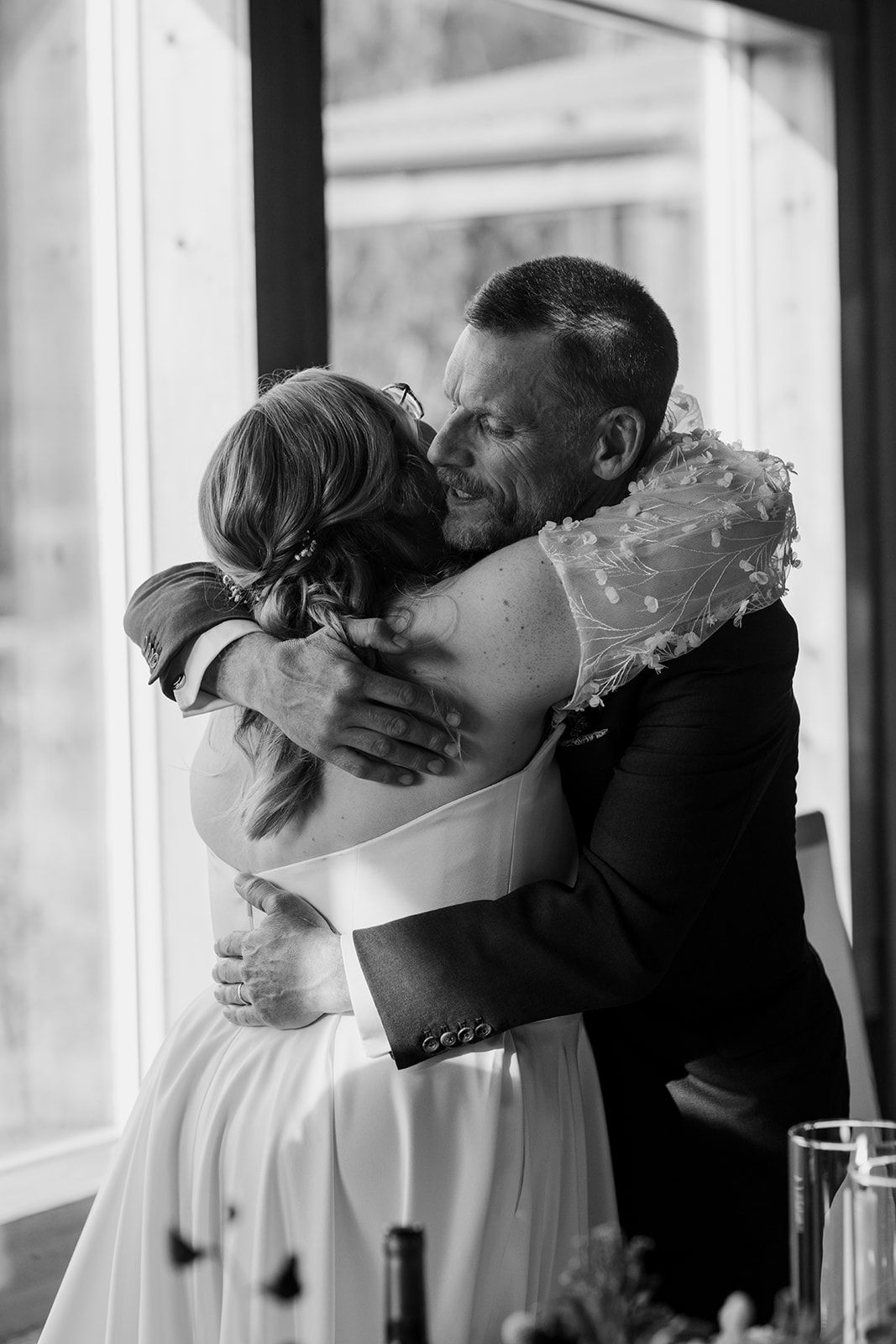 Emotional embrace between bride and loved one in black and white portrait.