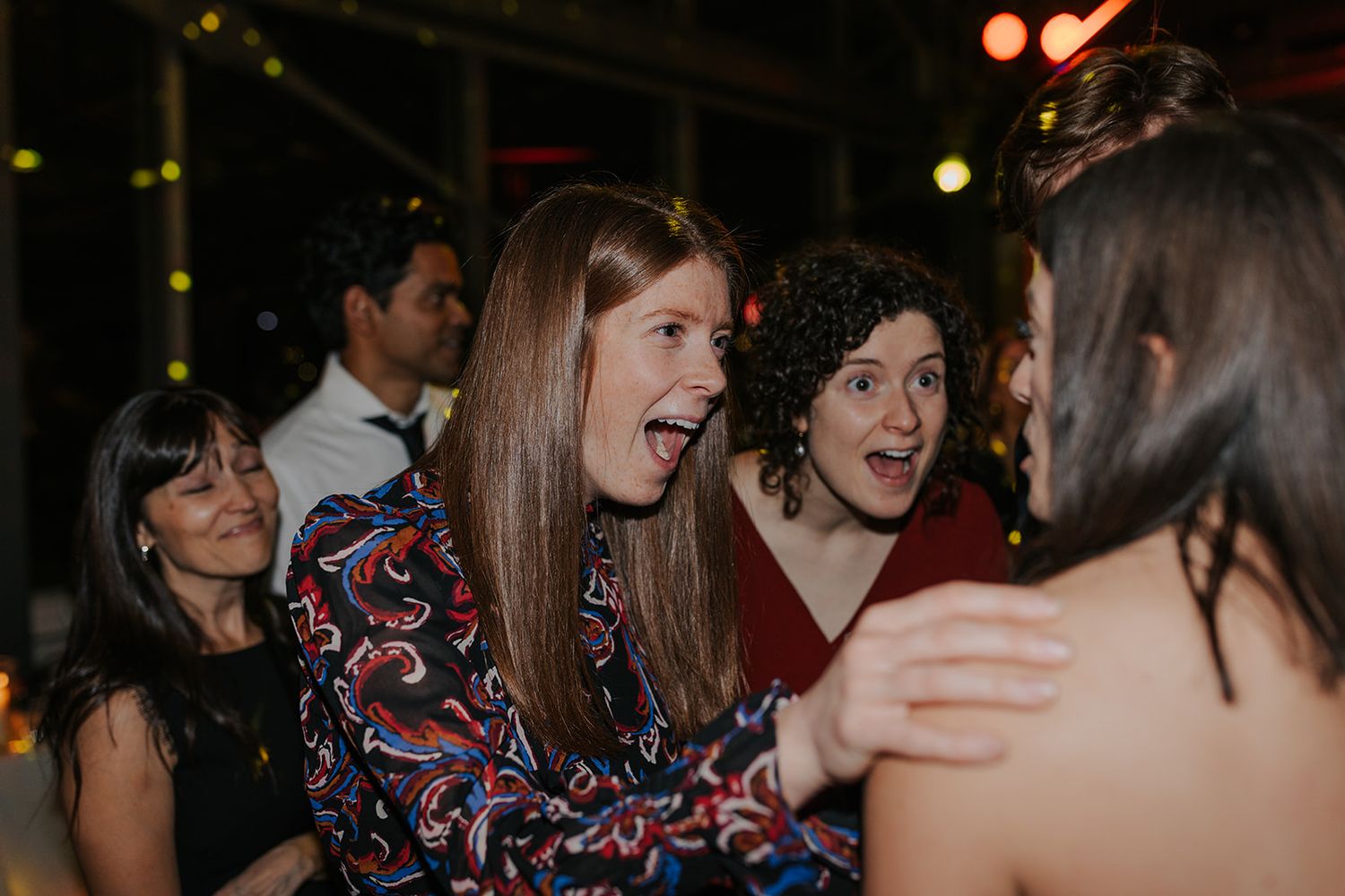 Party guests enjoying themselves under warm lighting at an evening celebration.